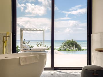 a bathroom with a tub and a pool outside