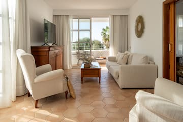 a living room with white furniture and a television