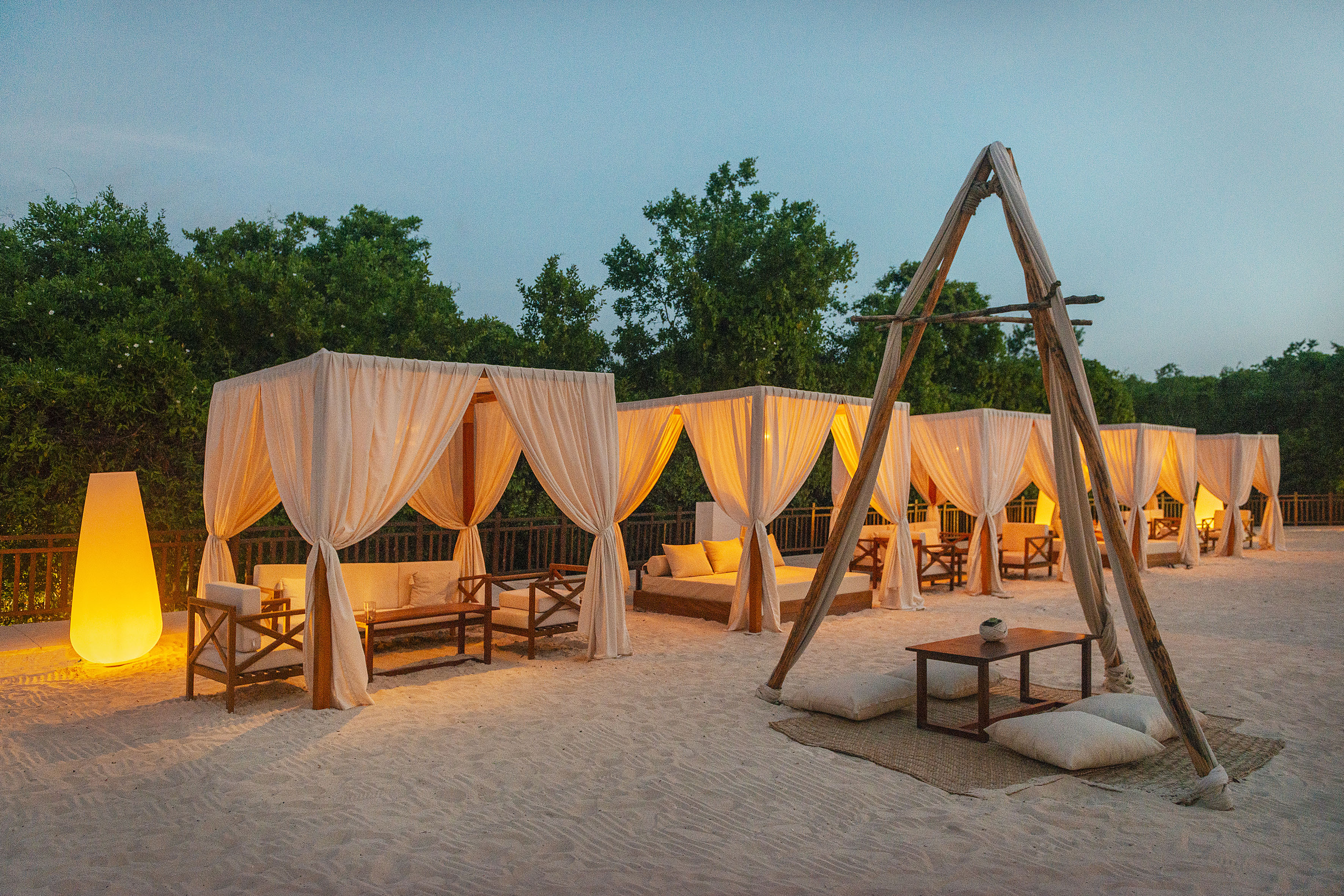 a group of tents with white curtains and wooden tables