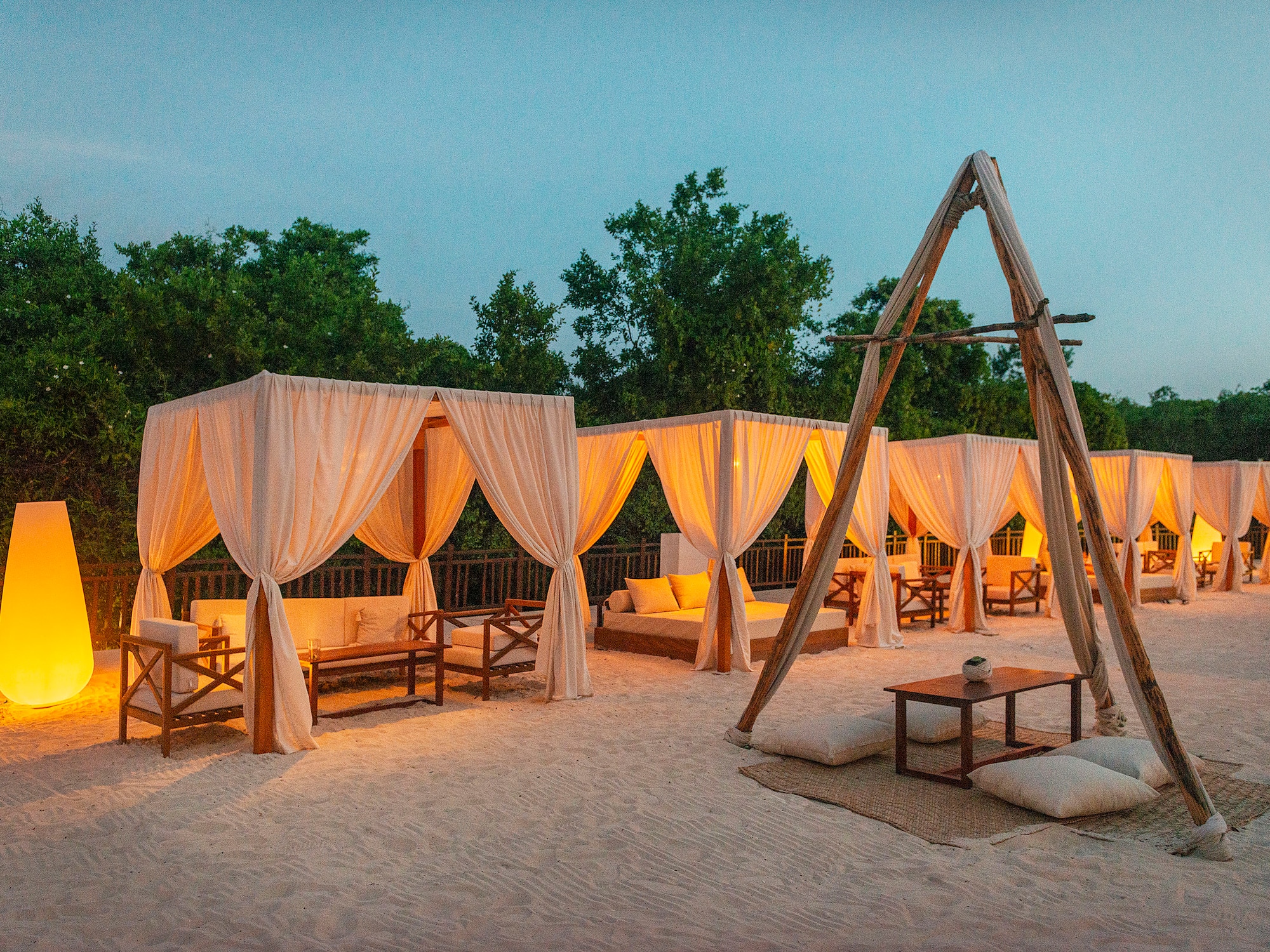 a group of tents with white curtains and wooden tables