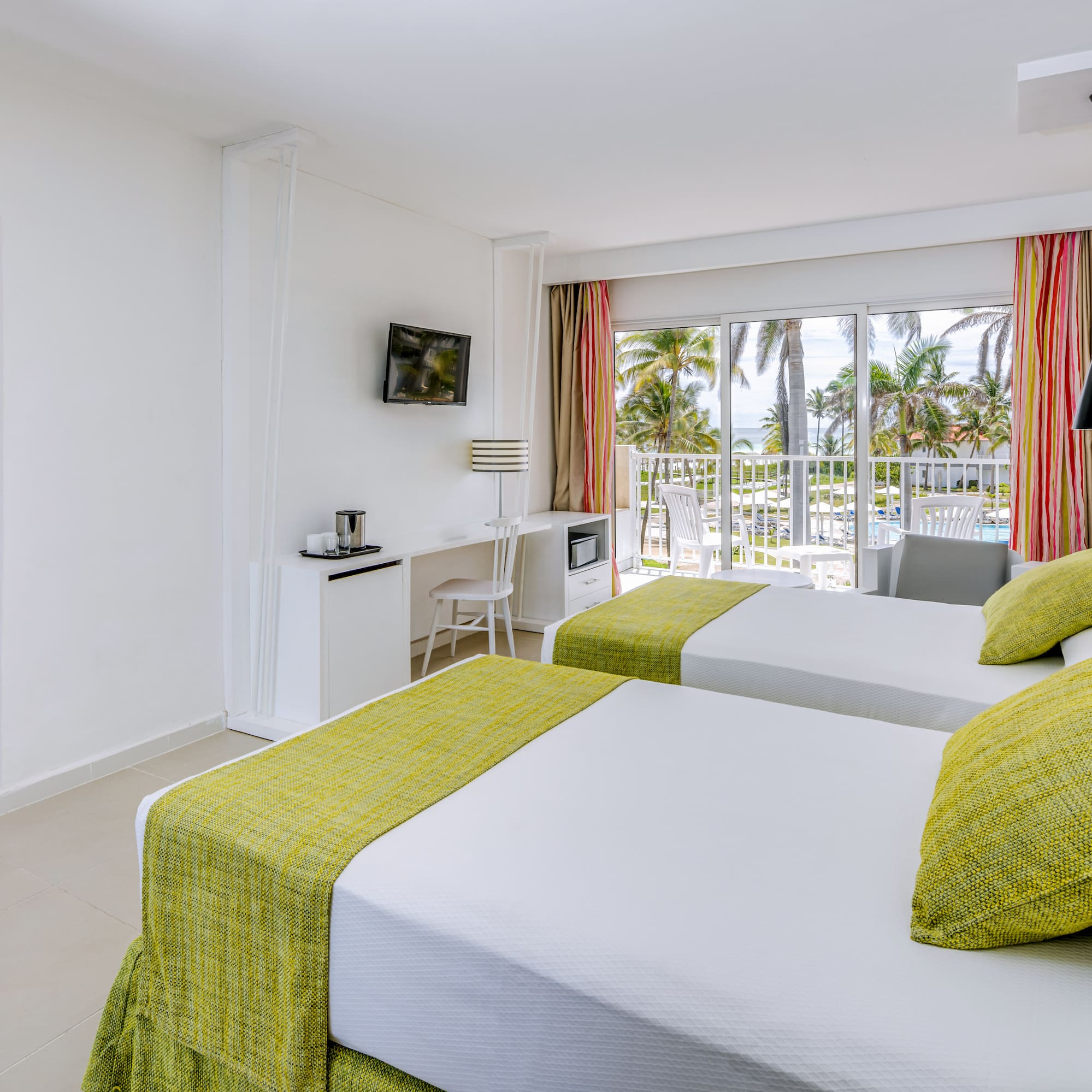 a room with two beds and a balcony with a view of the ocean