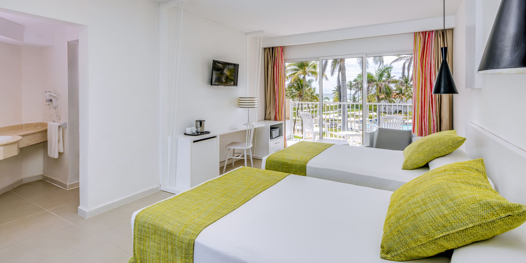 a room with two beds and a balcony with a view of the ocean