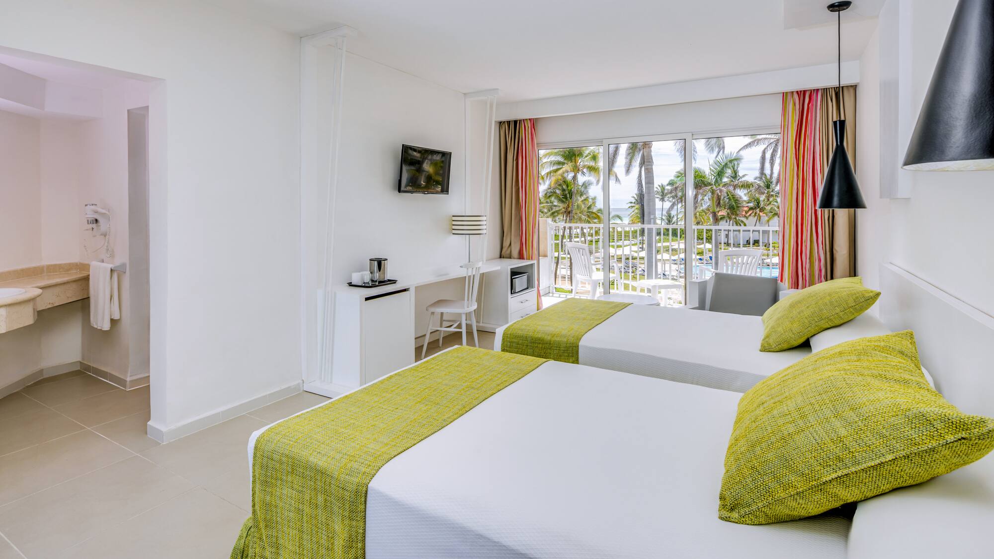 a room with two beds and a balcony with a view of the ocean