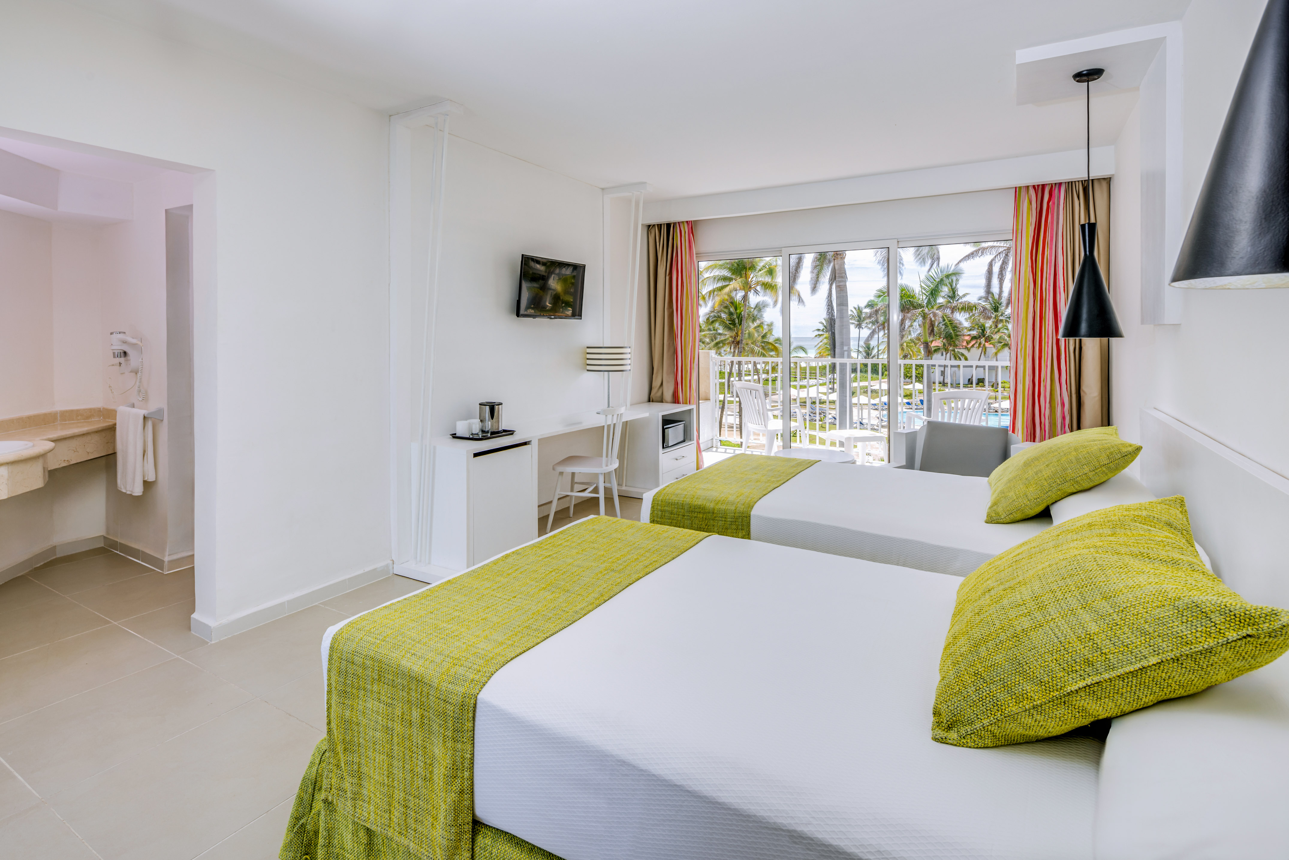 a room with two beds and a balcony with a view of the ocean