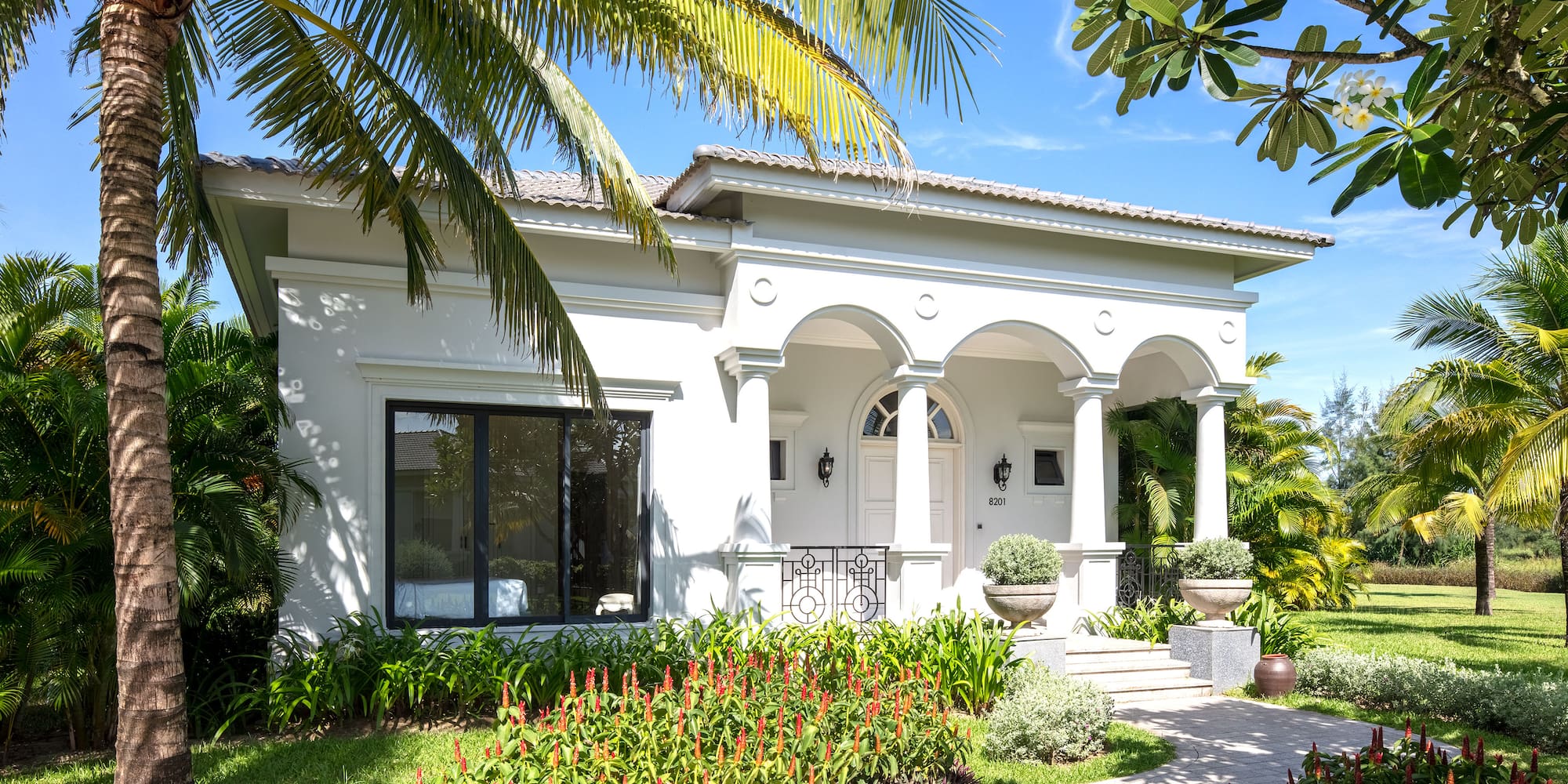 a white house with a walkway and palm trees