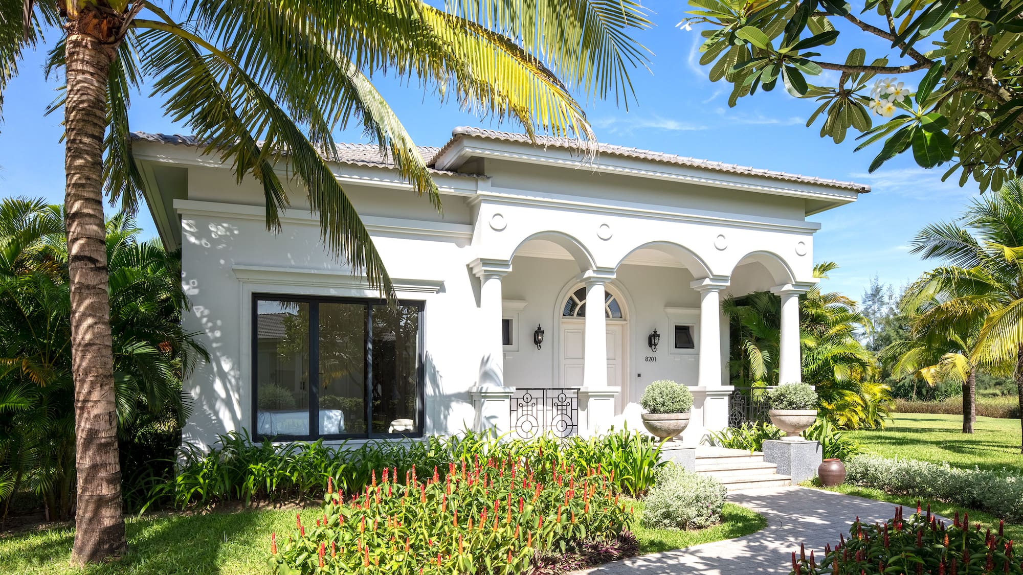 a white house with a walkway and palm trees