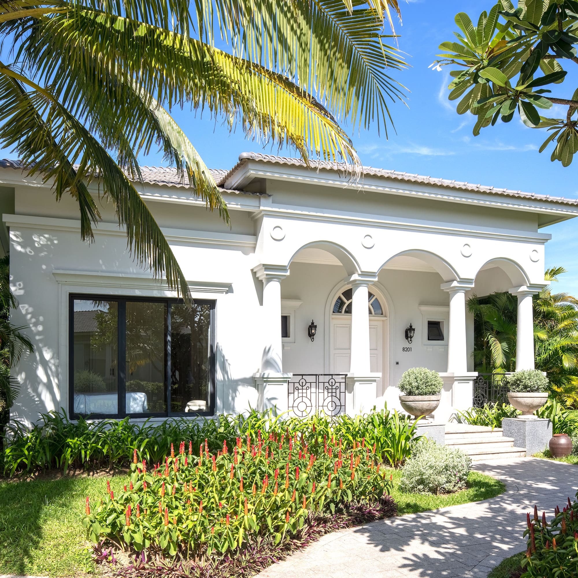 a white house with a walkway and palm trees