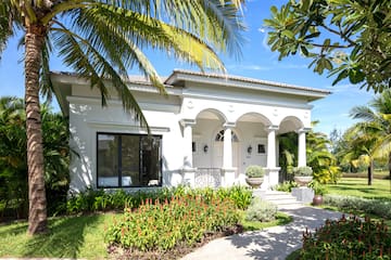 a white house with a walkway and palm trees