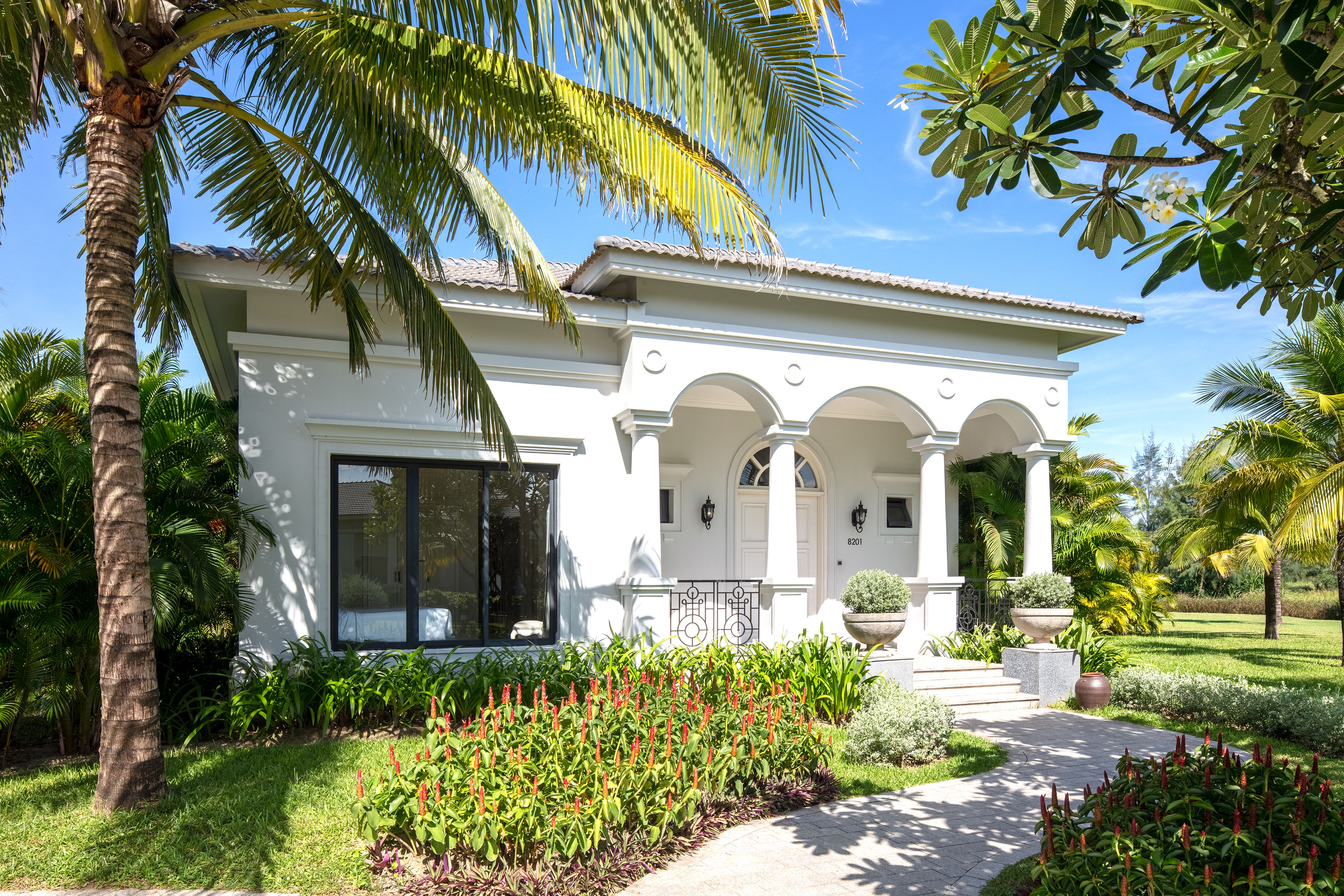 a white house with a walkway and palm trees