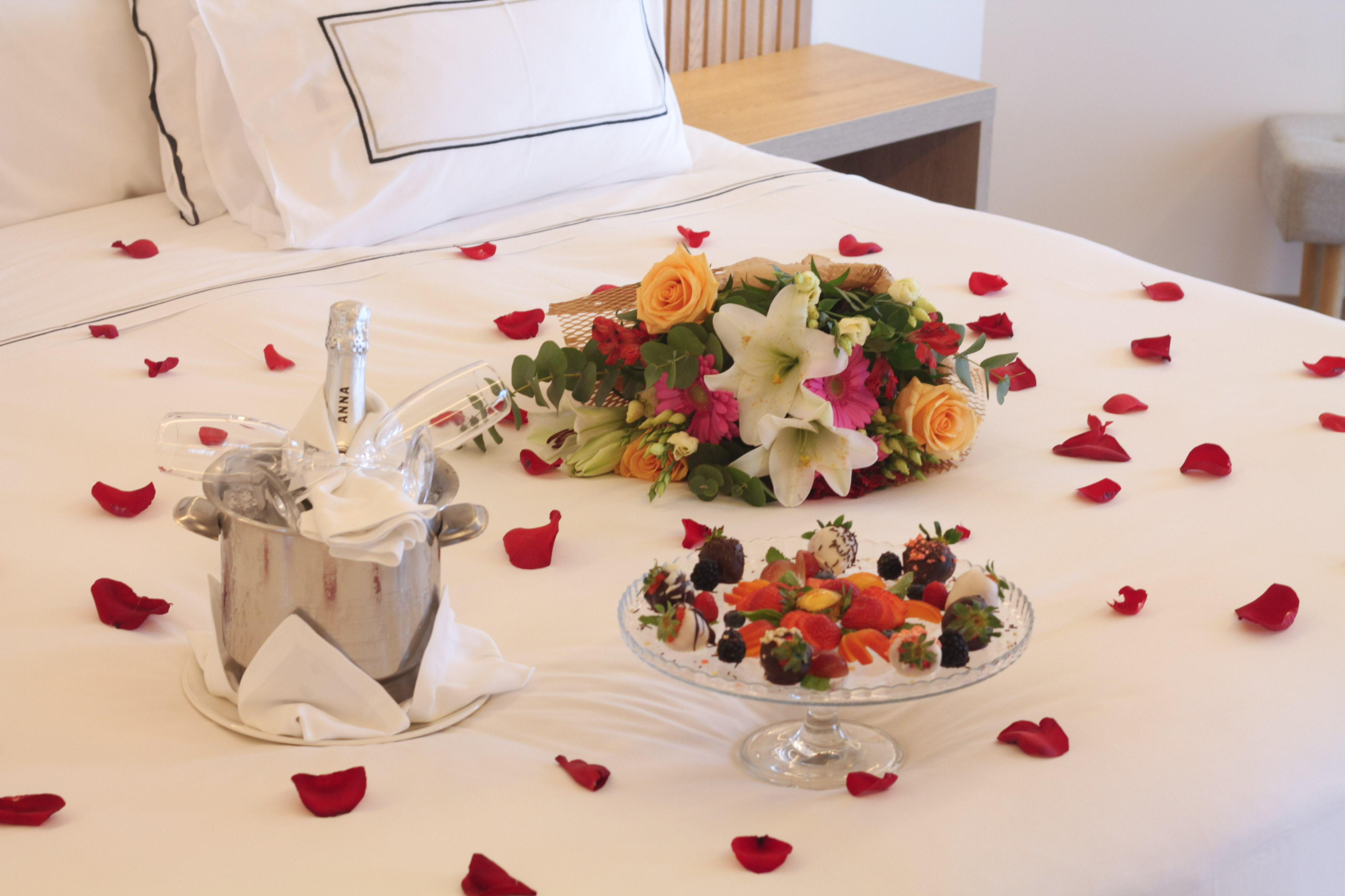 a bed with a champagne bottle and fruit on it