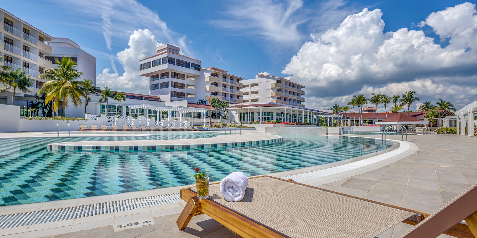 a pool with a lounge chair and a glass of water