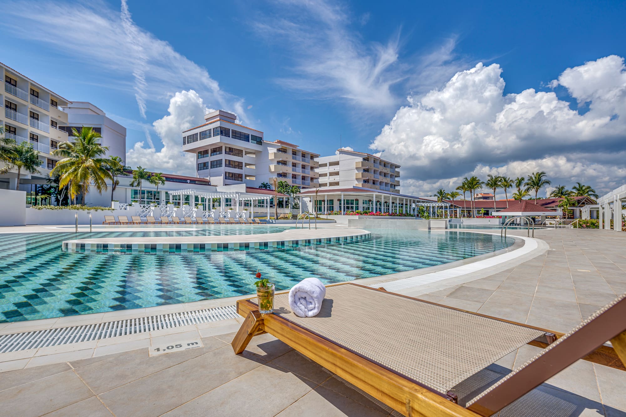 a pool with a lounge chair and a glass of water