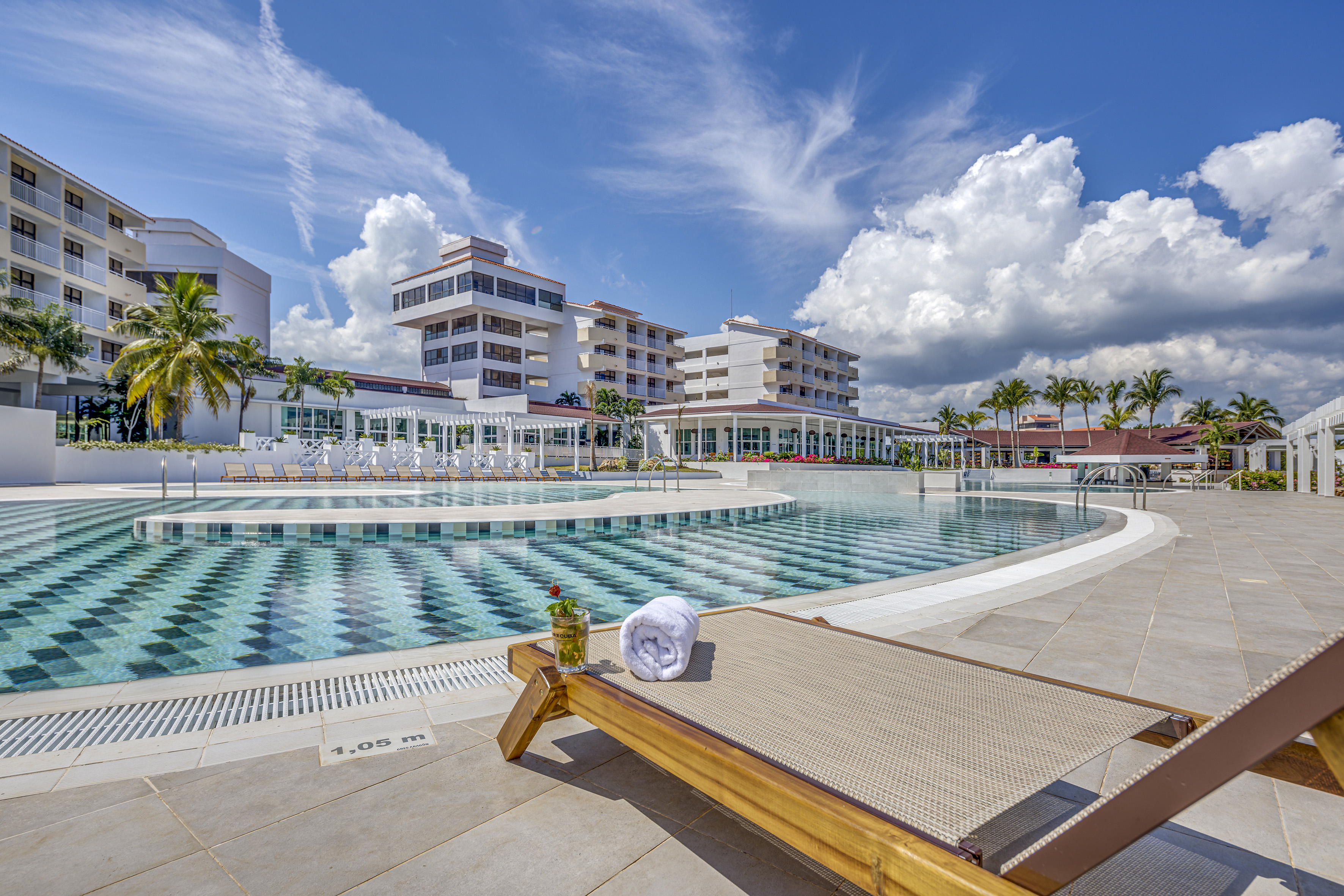 a pool with a lounge chair and a glass of water
