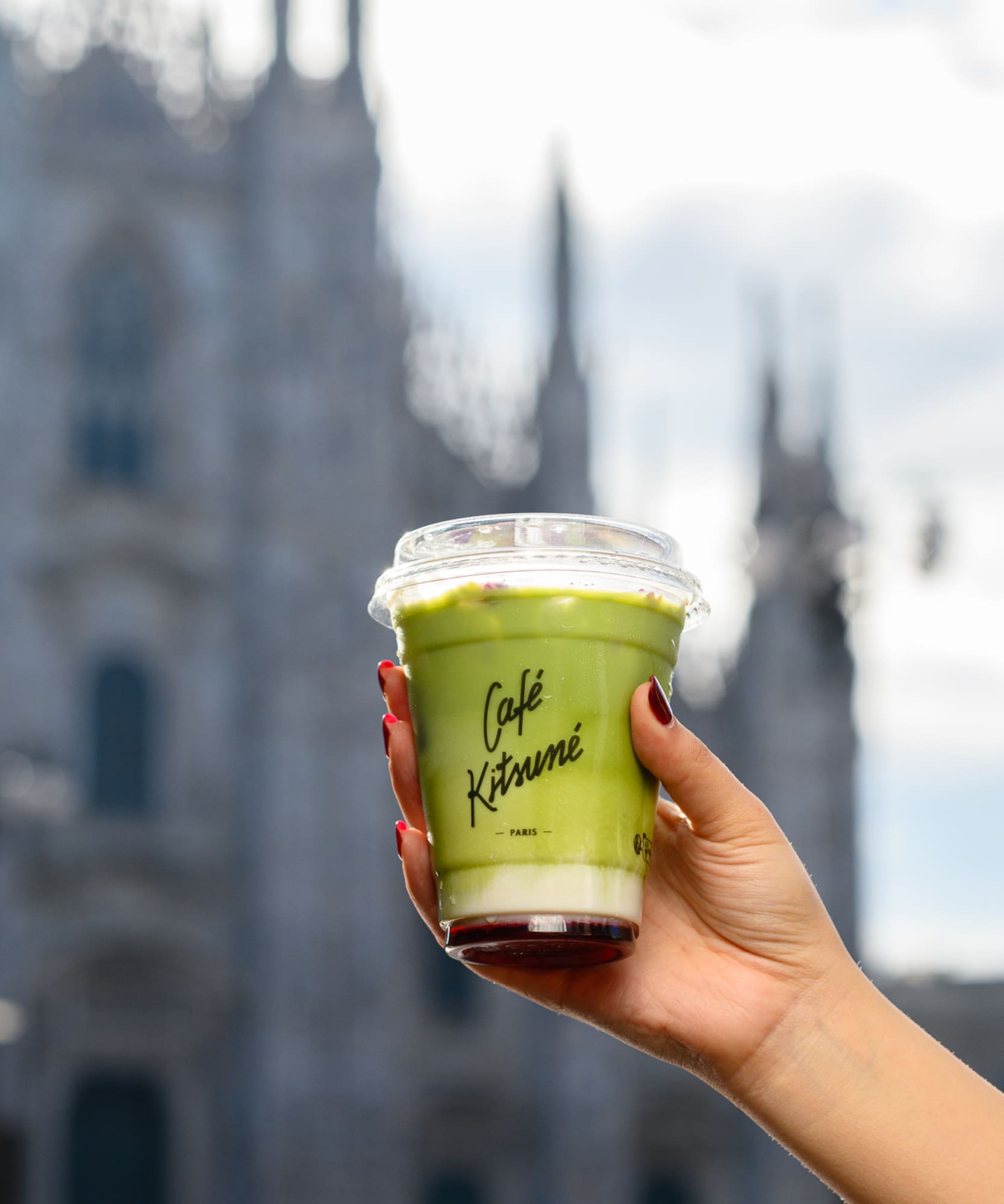 a hand holding a cup of green liquid
