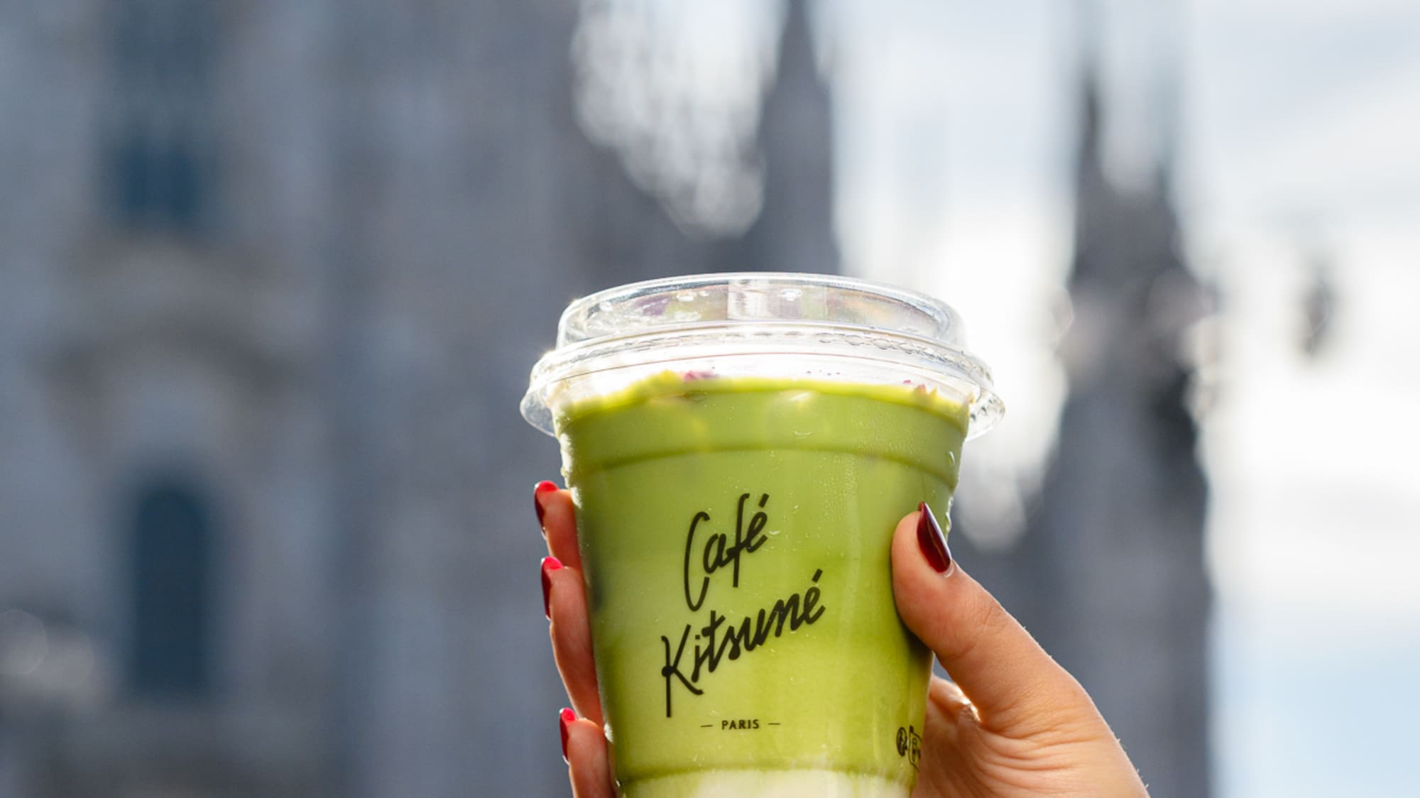 a hand holding a cup of green liquid