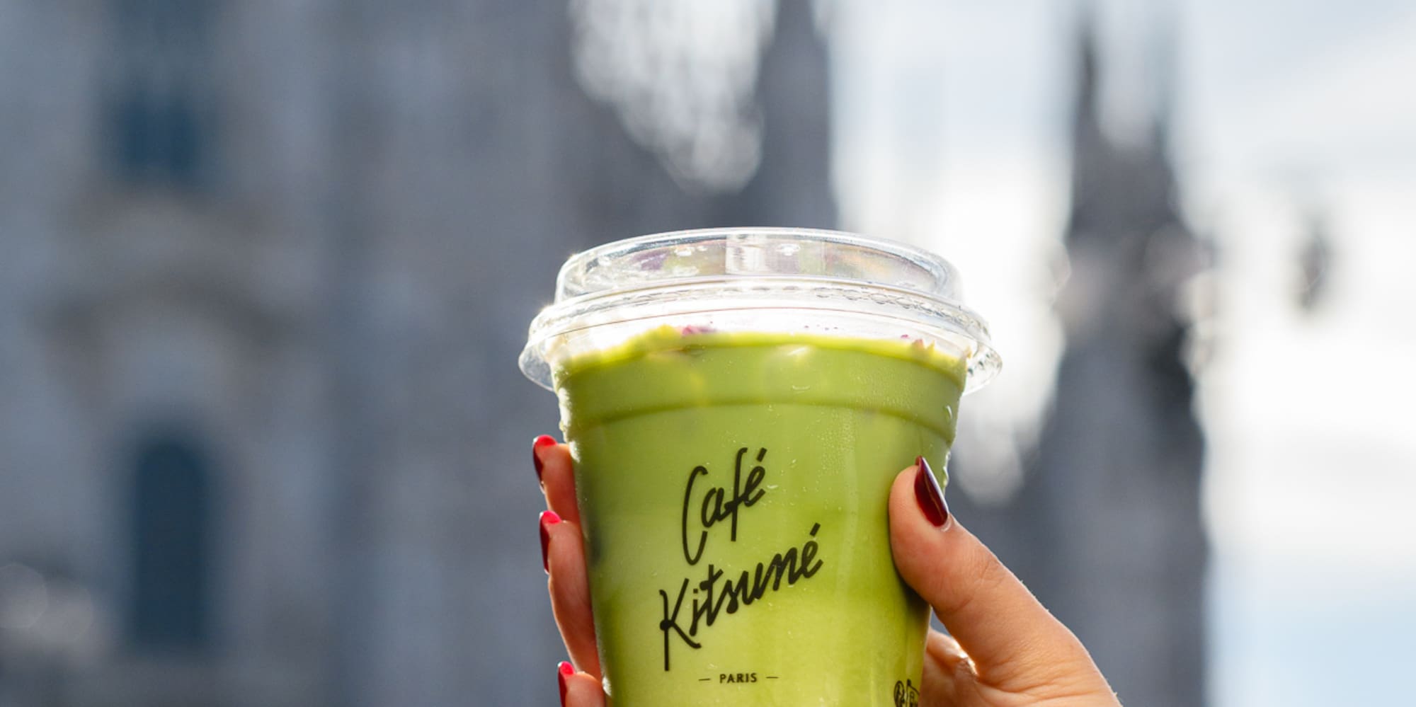 a hand holding a cup of green liquid