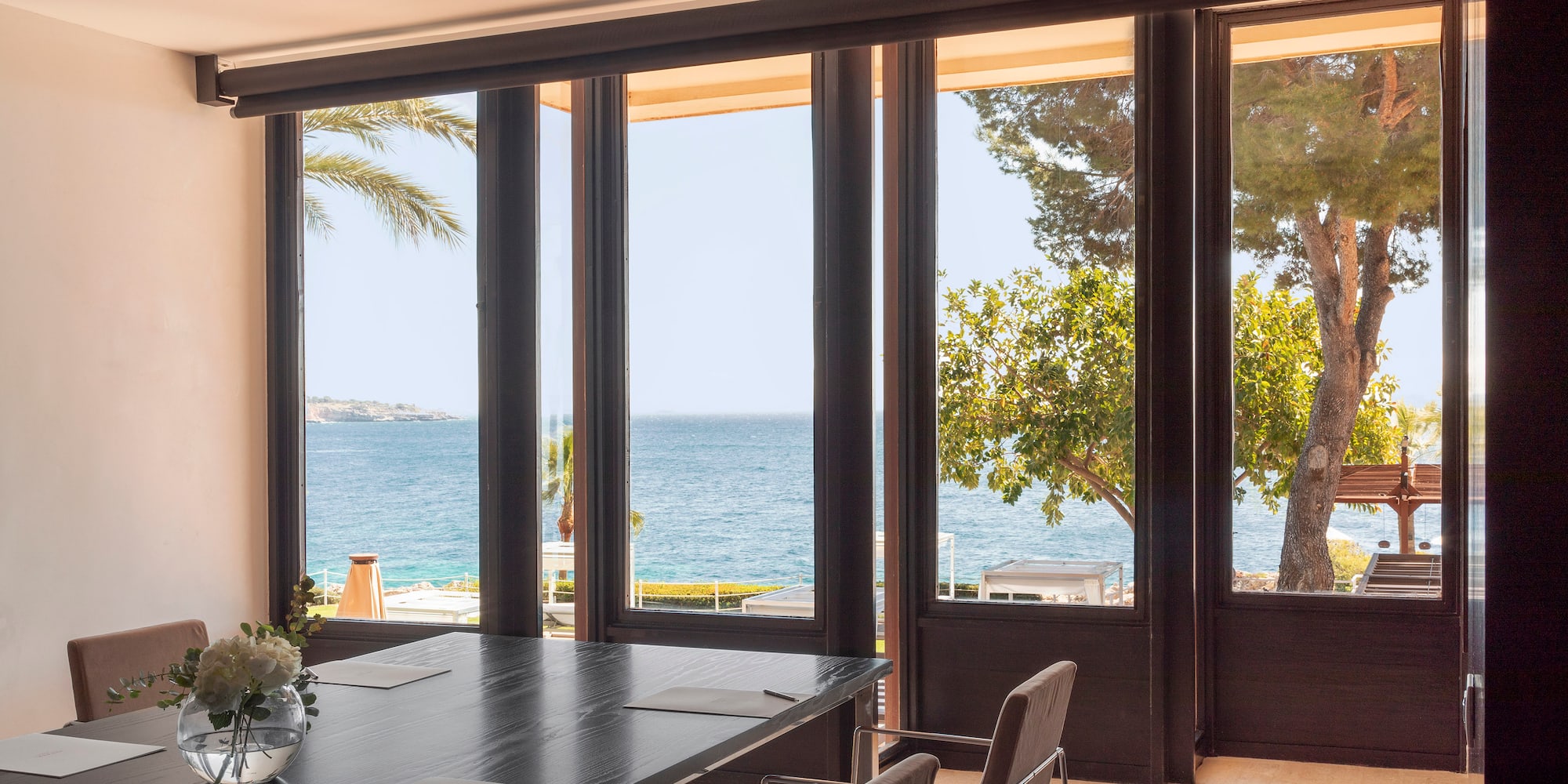 a room with a table and chairs overlooking the ocean