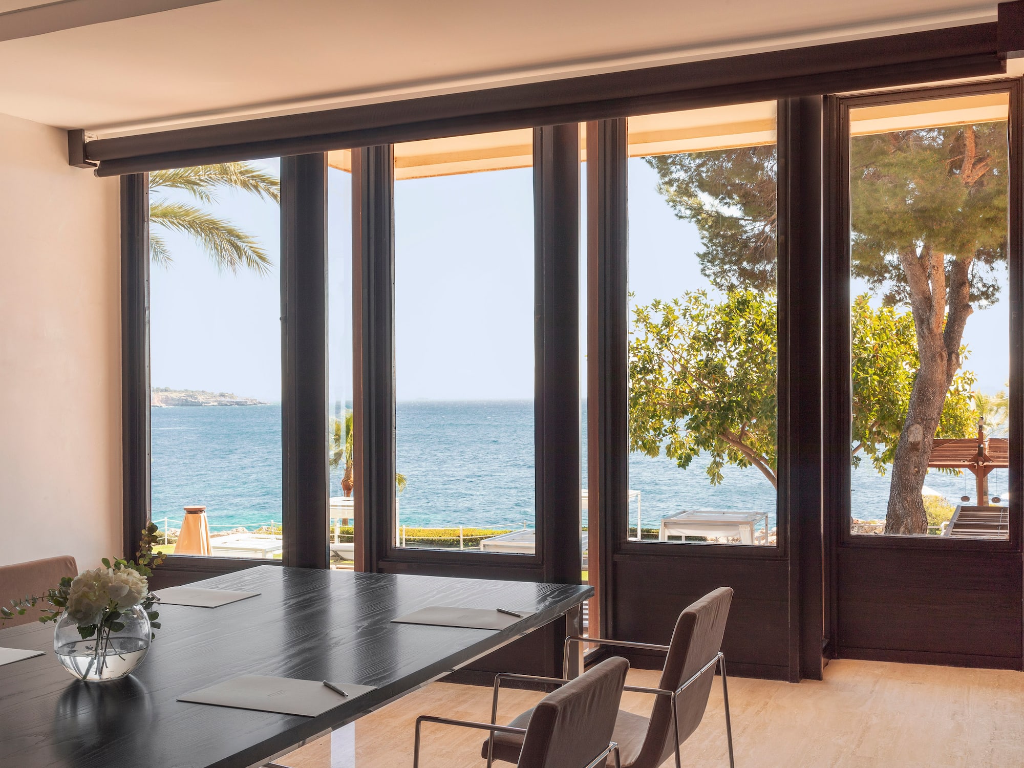 a room with a table and chairs overlooking the ocean