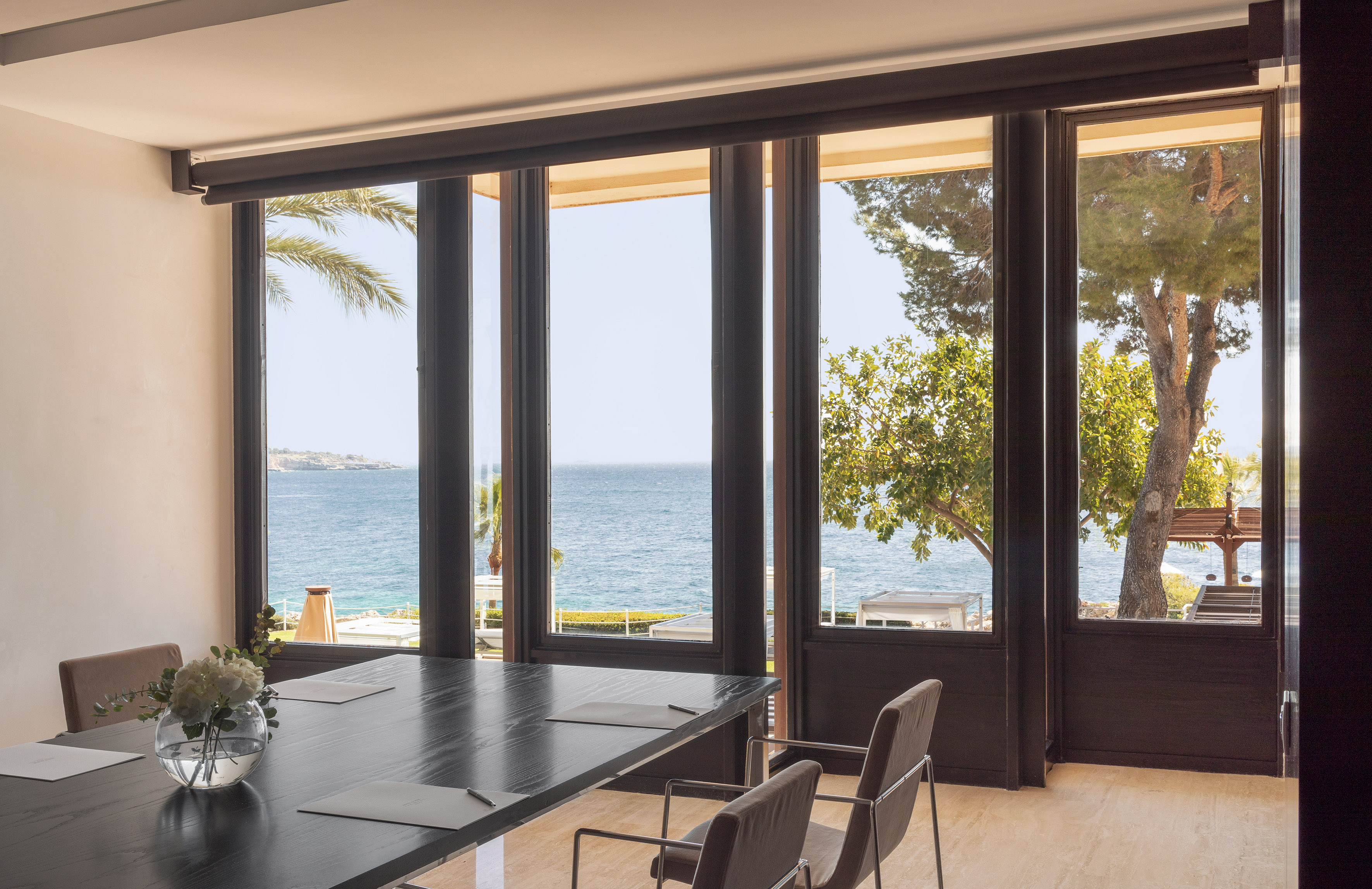 Coastal meeting room with ocean view, dark table, and modern decor.