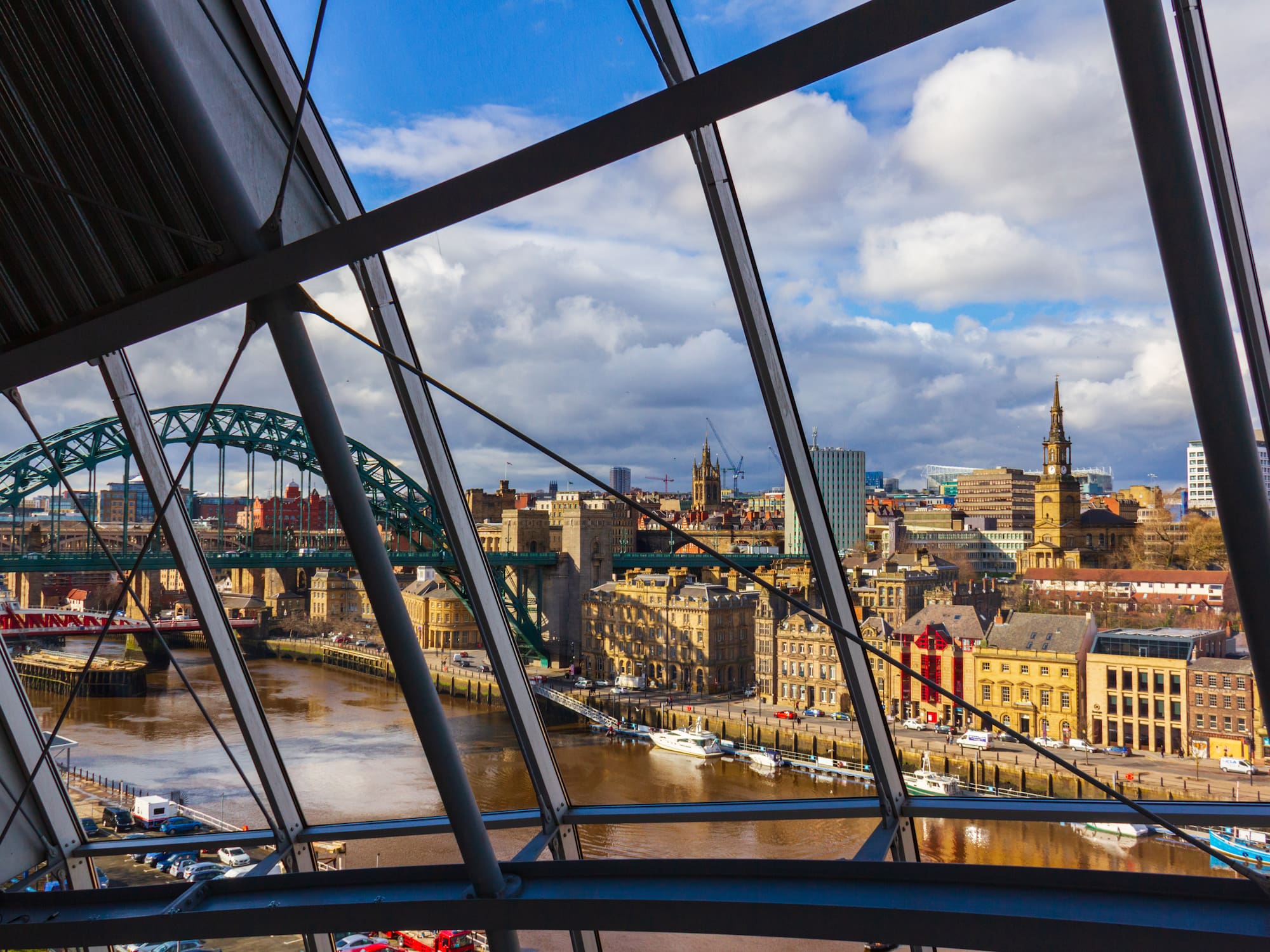 Newcastle city skyline through modern window, Tyne Bridge over River Tyne.