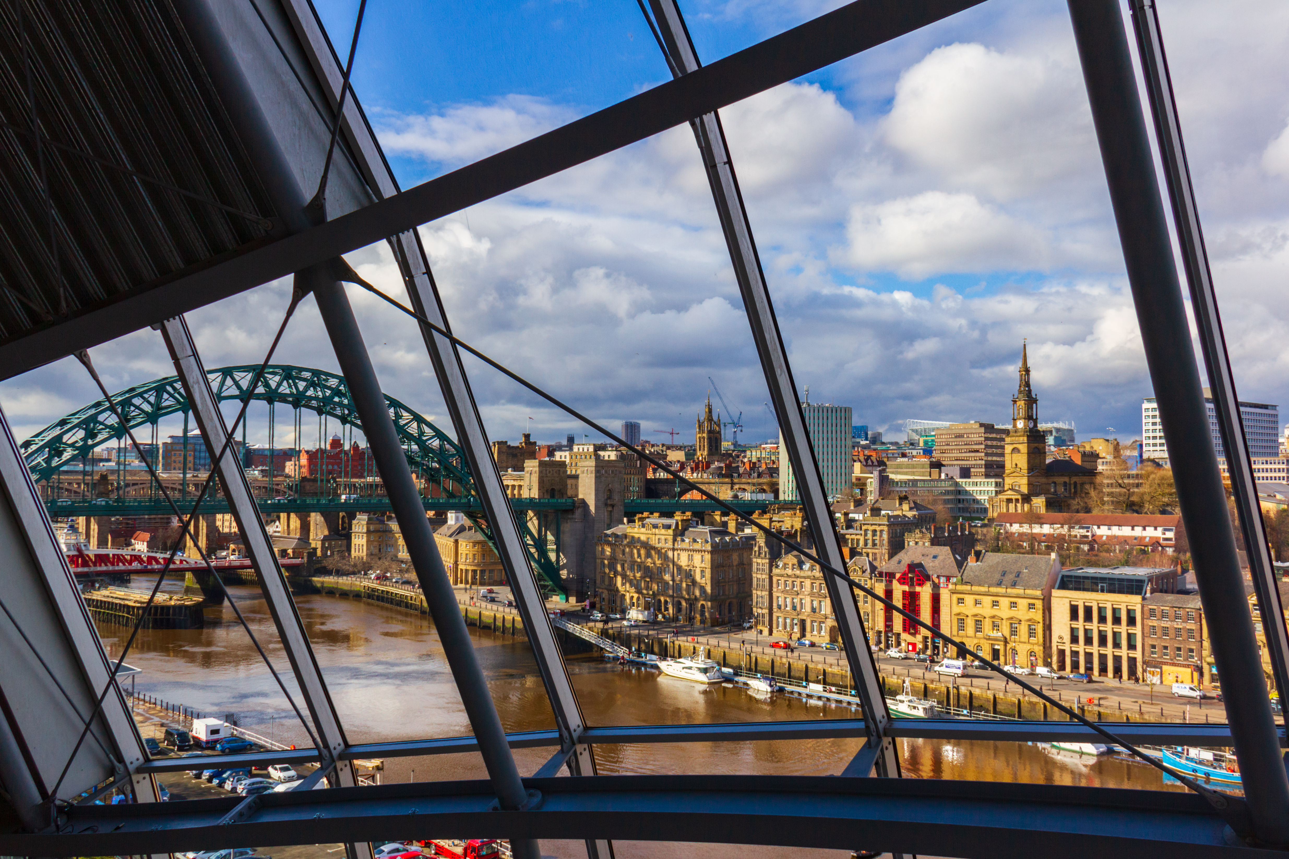 Newcastle city skyline through modern window, Tyne Bridge over River Tyne.