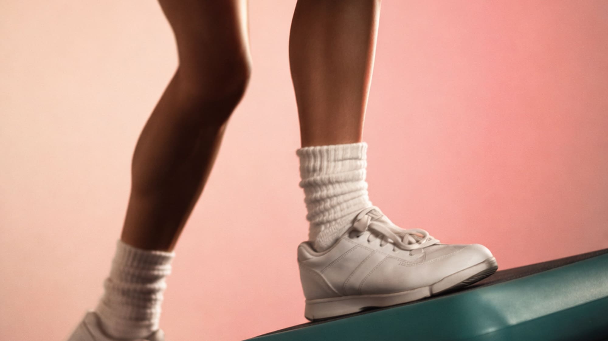 Legs in red shorts and white sneakers performing step aerobics on stacked platforms.