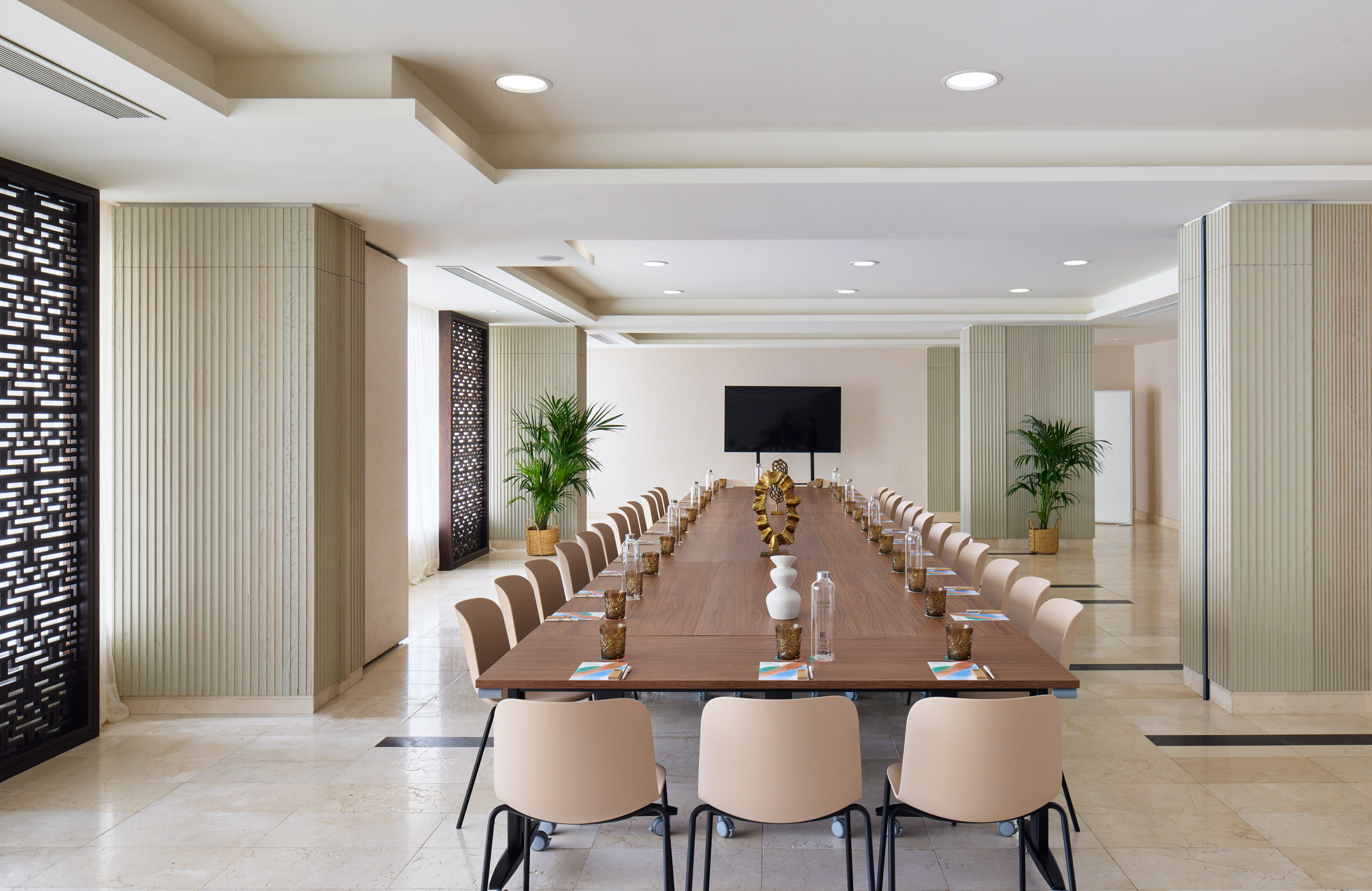 Modern U-shaped conference room with table, chairs, and large TV screen.