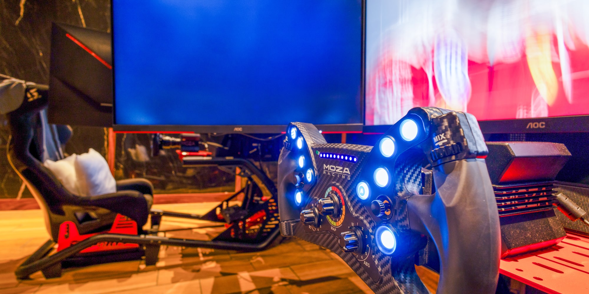 Moza Racing sim racing cockpit with illuminated wheel and gaming monitors.
