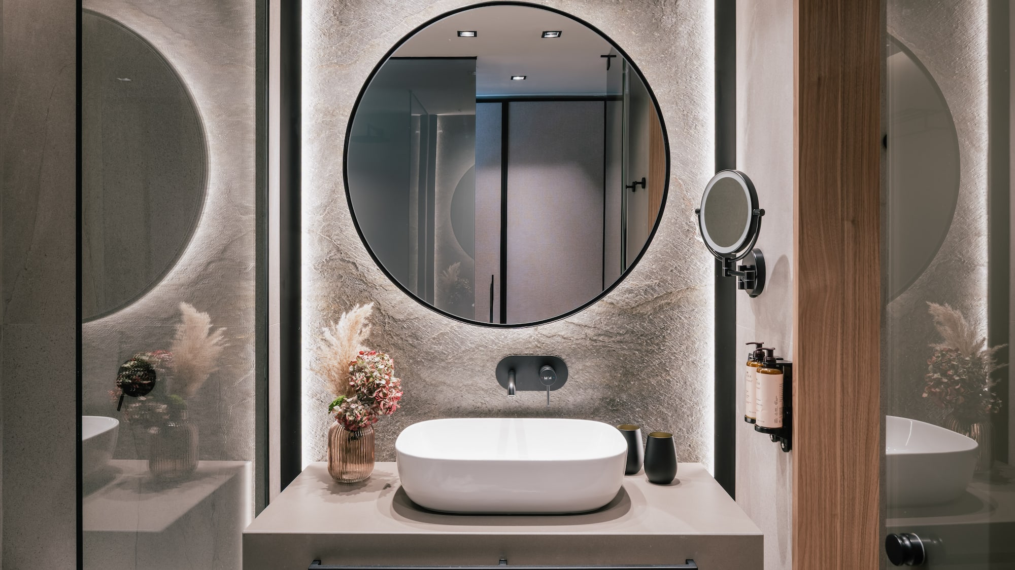 Modern bathroom vanity with round backlit mirror, white vessel sink, and concrete wall.