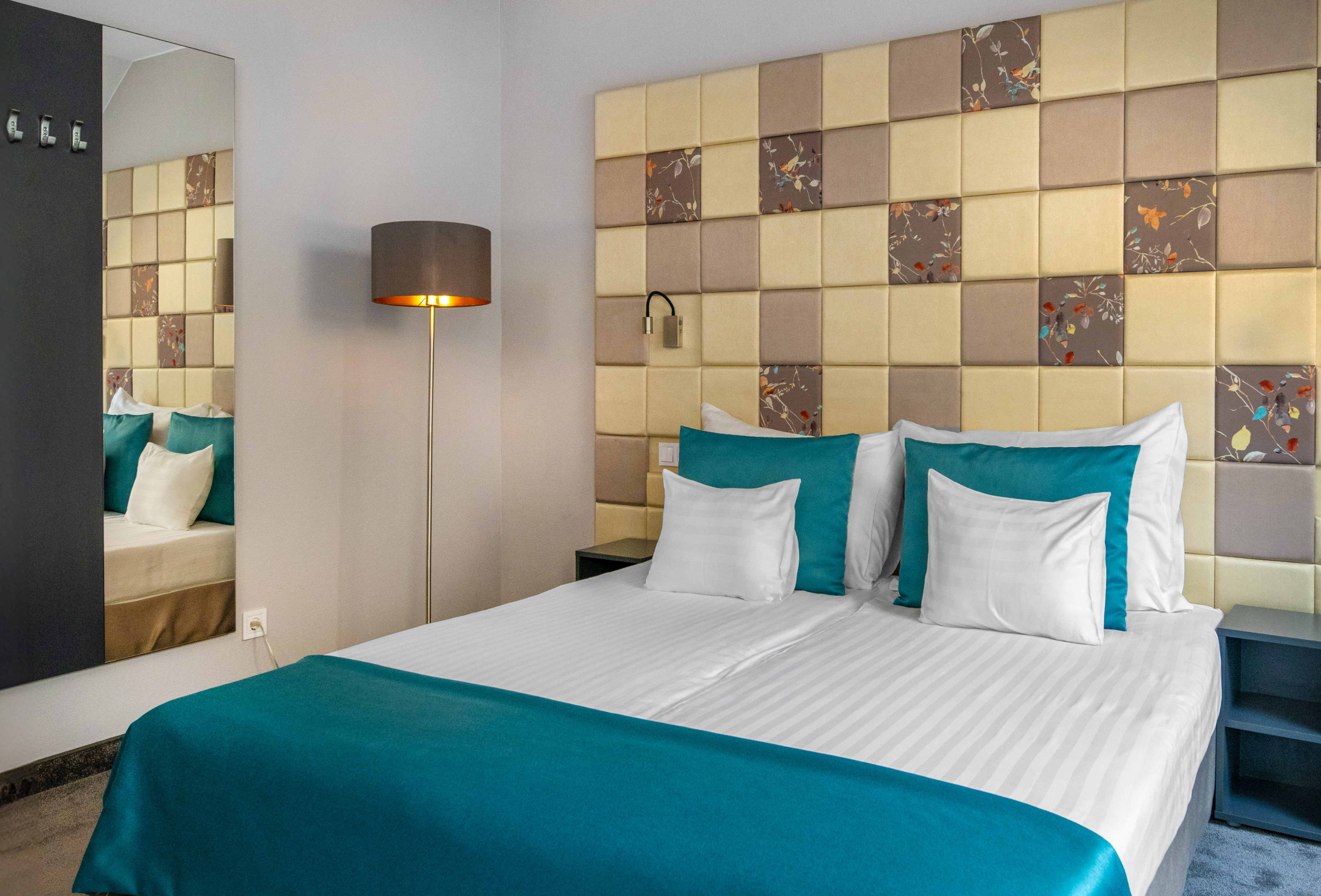 a bed with a lamp and a mirror