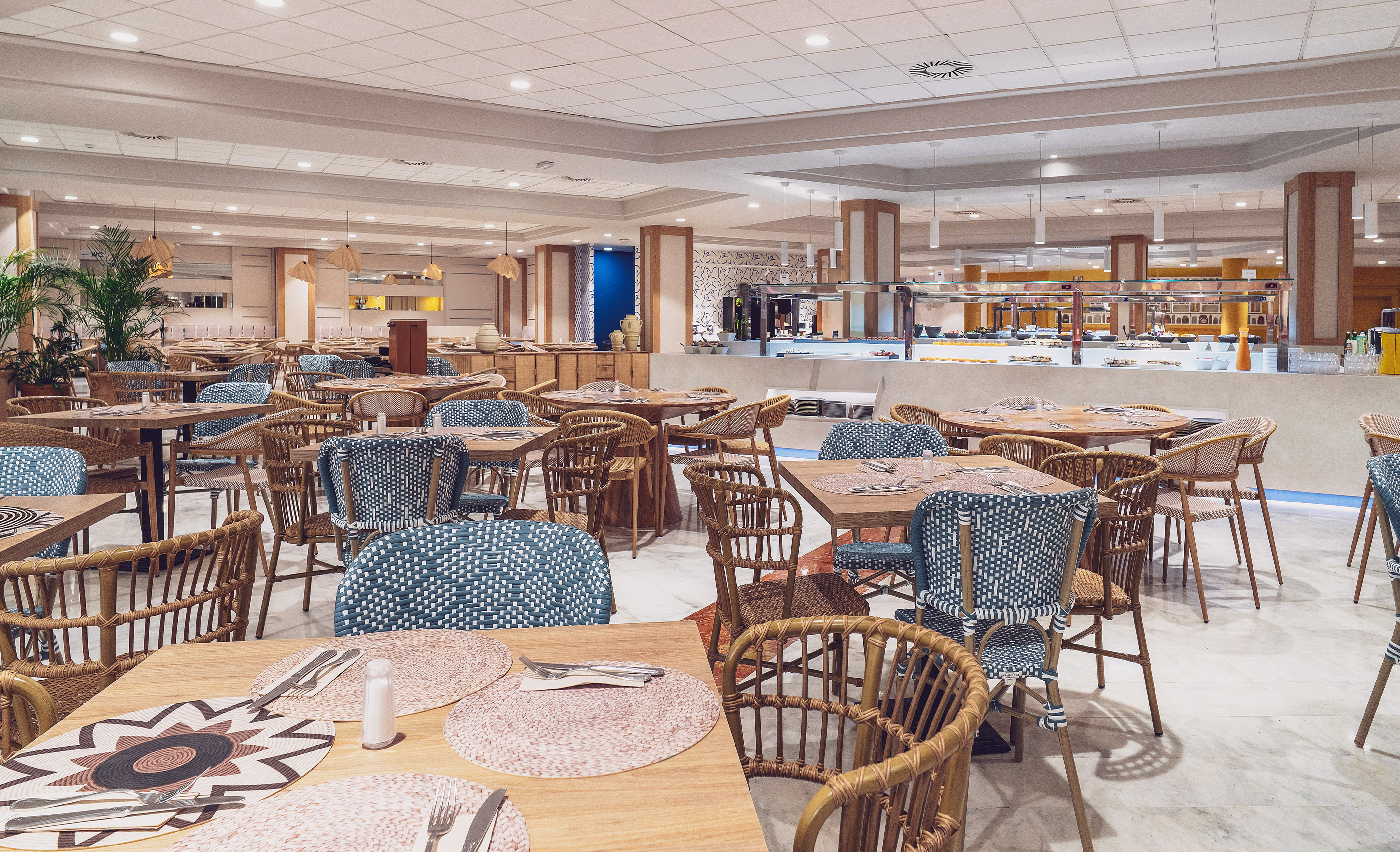 Bright hotel buffet dining room with set tables and woven rattan chairs.