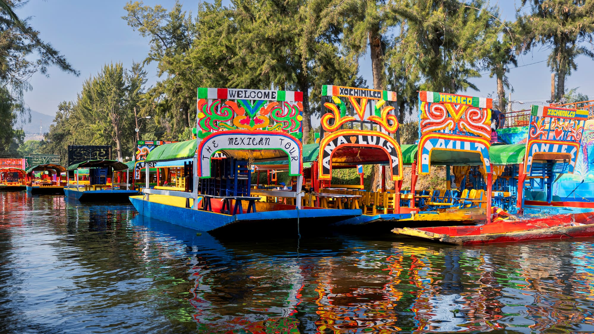 a group of boats on water with Xochimilco in the background