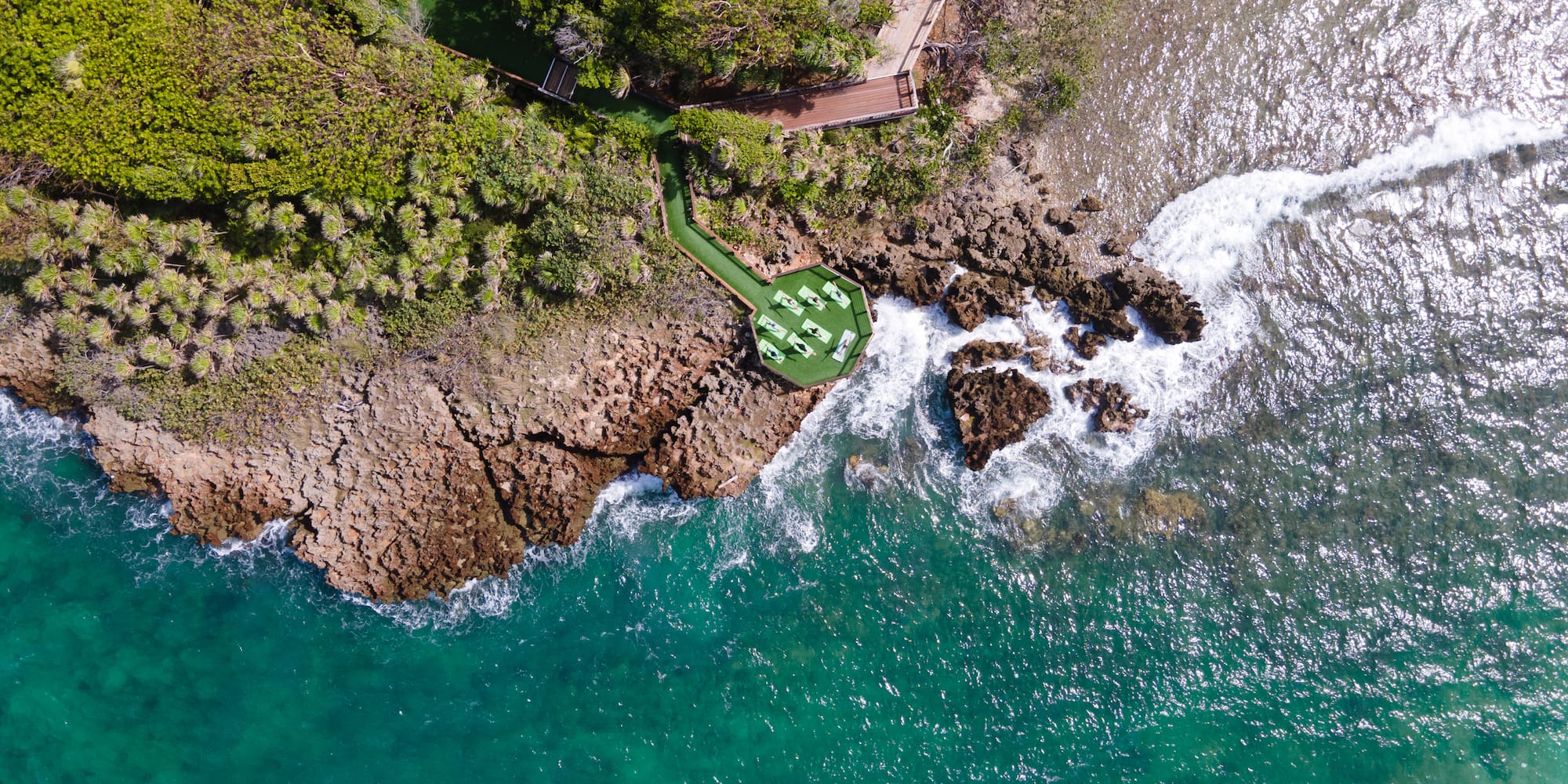 a aerial view of a beach with a deck and chairs on a rocky shore