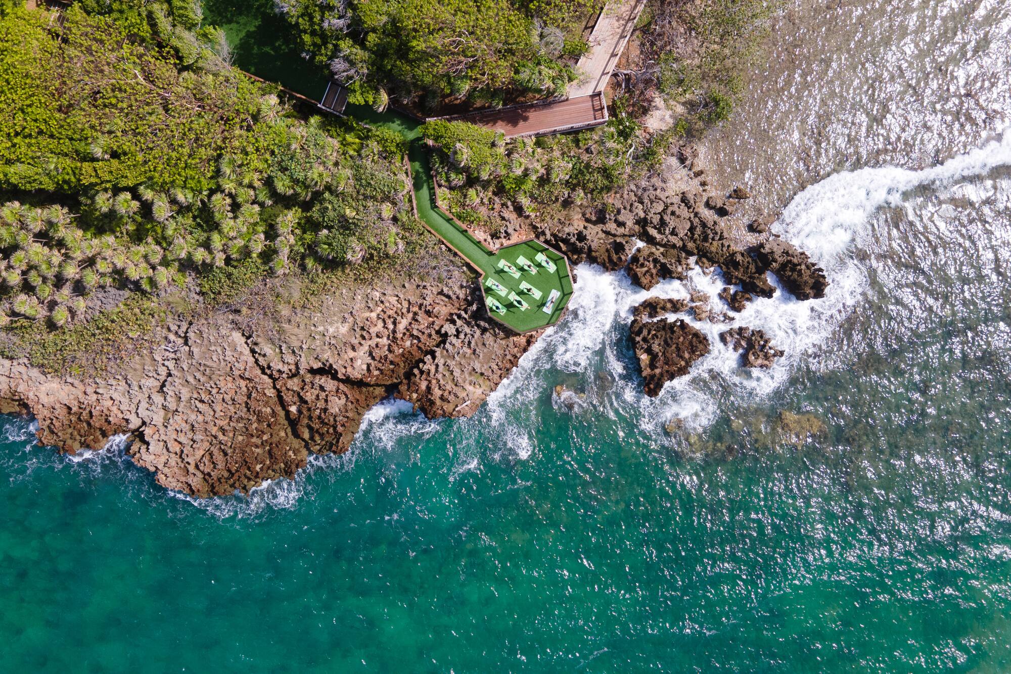 a aerial view of a beach with a deck and chairs on a rocky shore
