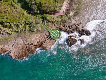 a aerial view of a beach with a deck and chairs on a rocky shore