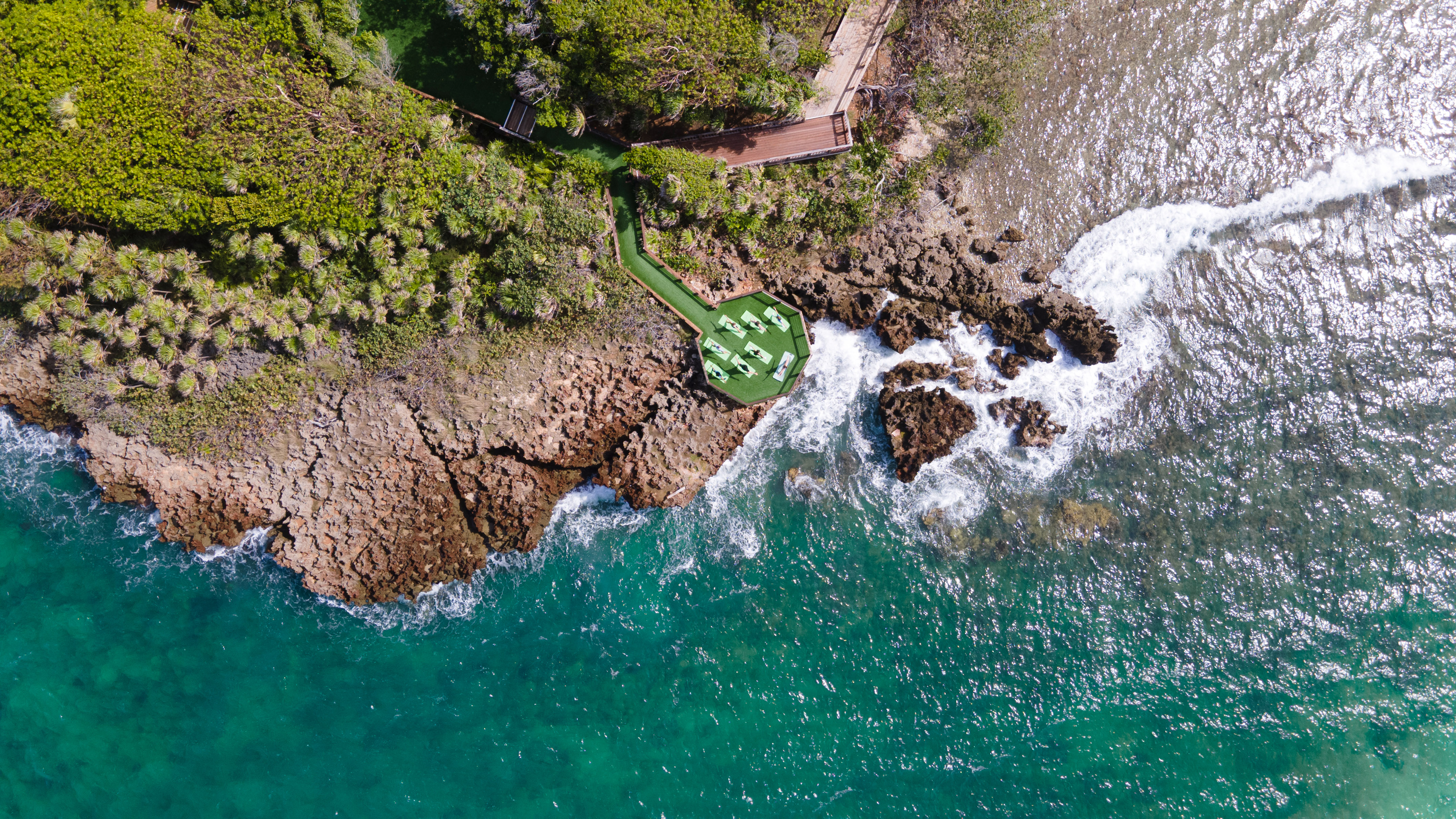 a aerial view of a beach with a deck and chairs on a rocky shore