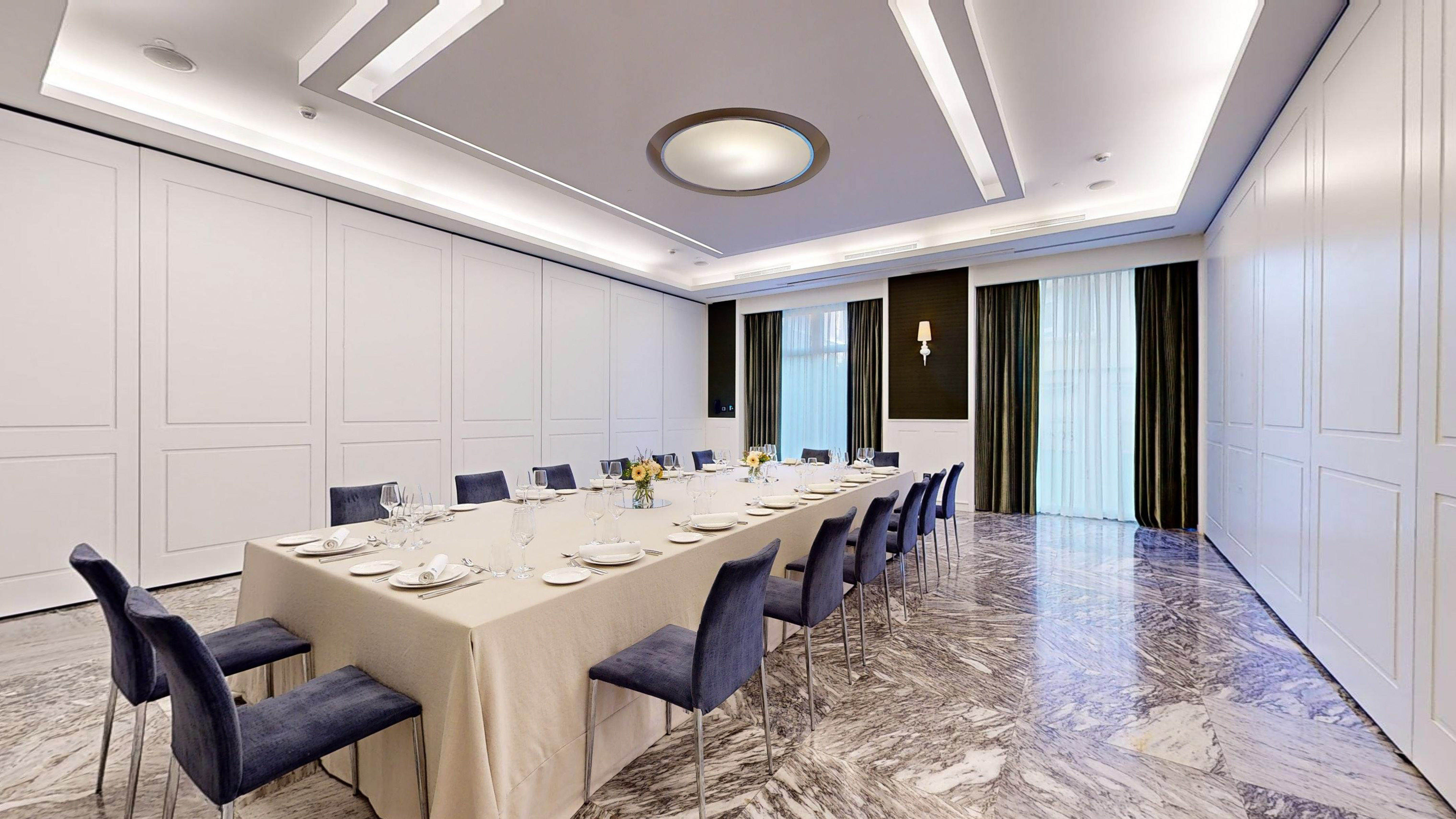 Luxury meeting room with long table, blue chairs, modern decor, marble floor.