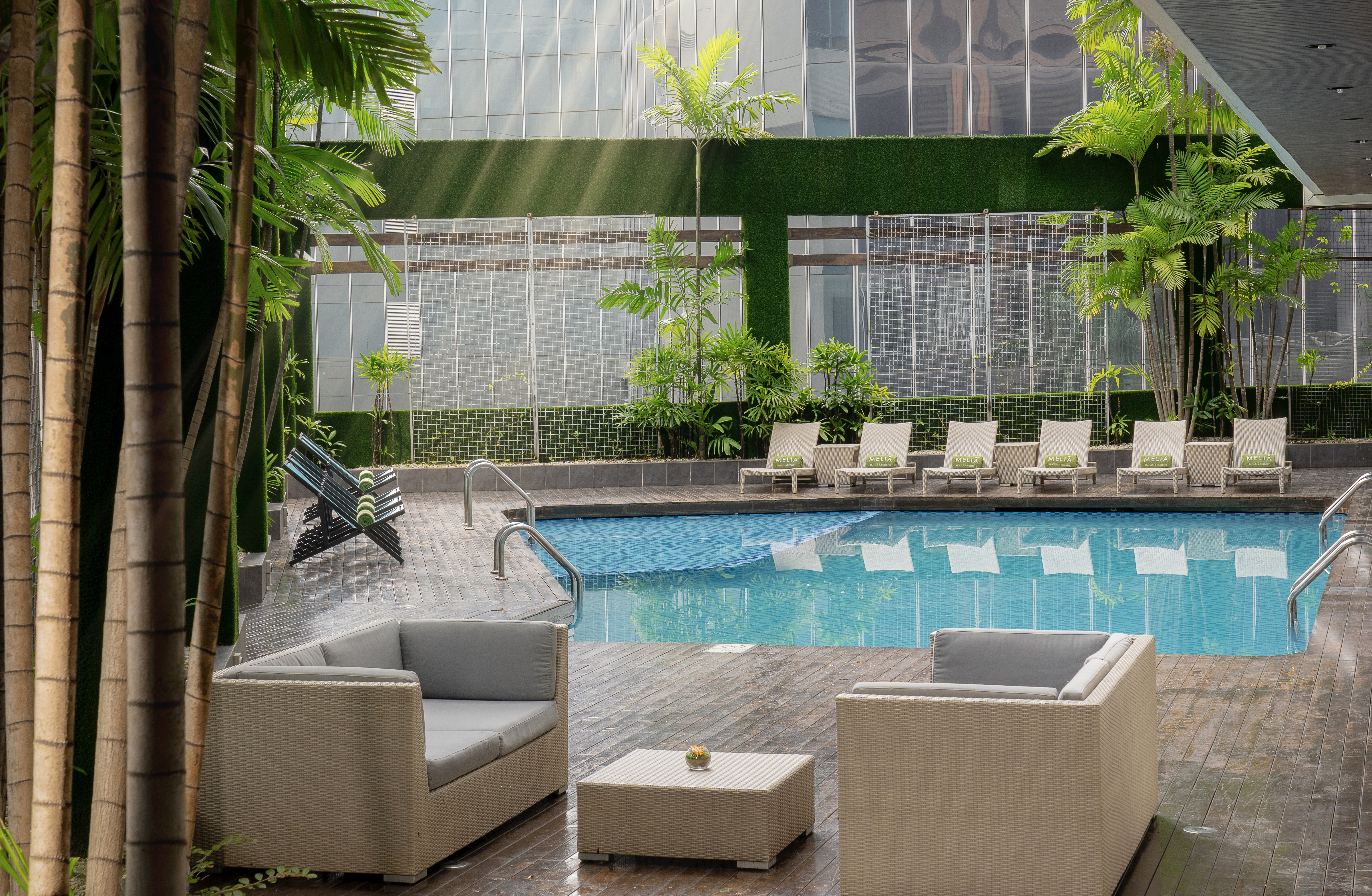 Melia resort pool deck with modern lounge seating and vibrant palm trees.