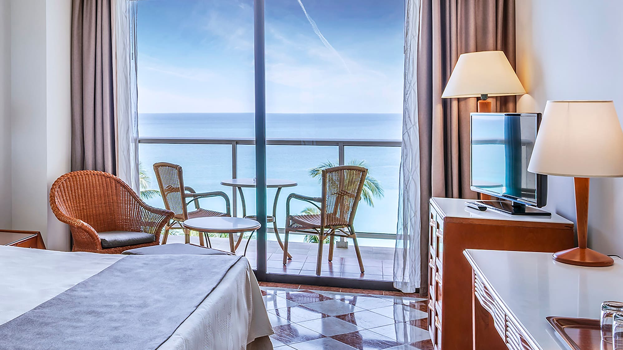 a room with a bed and a table and chairs and a balcony