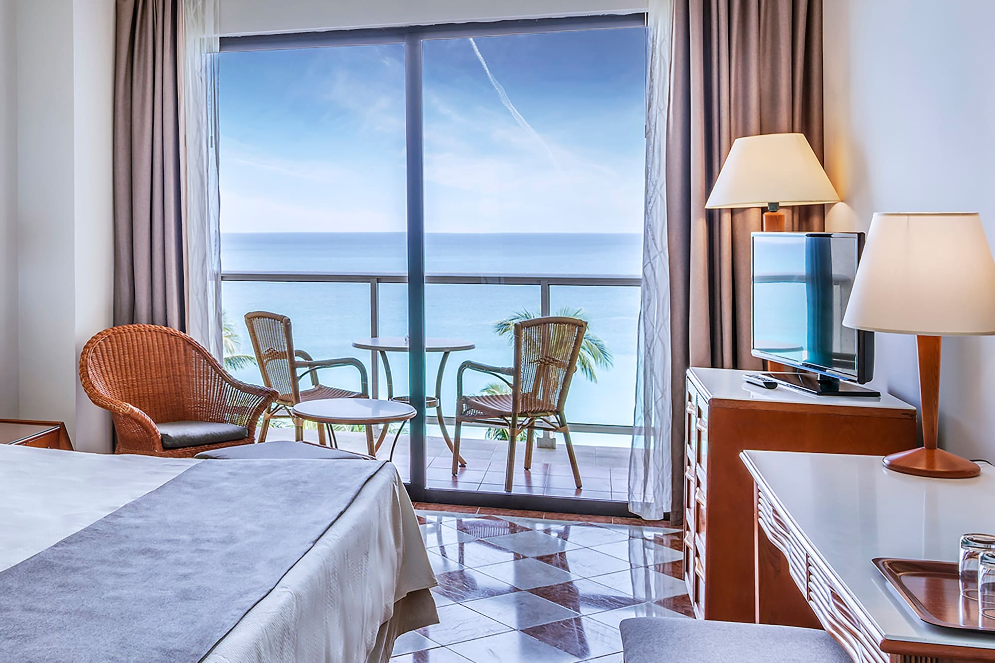 a room with a bed and a table and chairs and a balcony