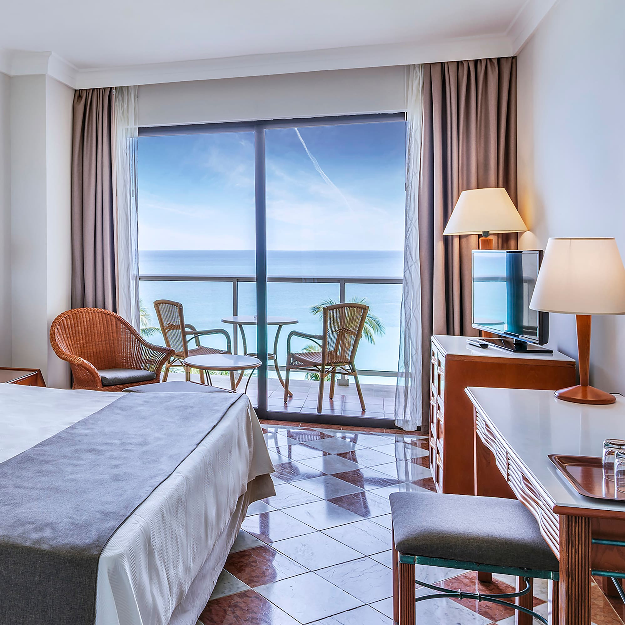 a room with a bed and a table and chairs and a balcony