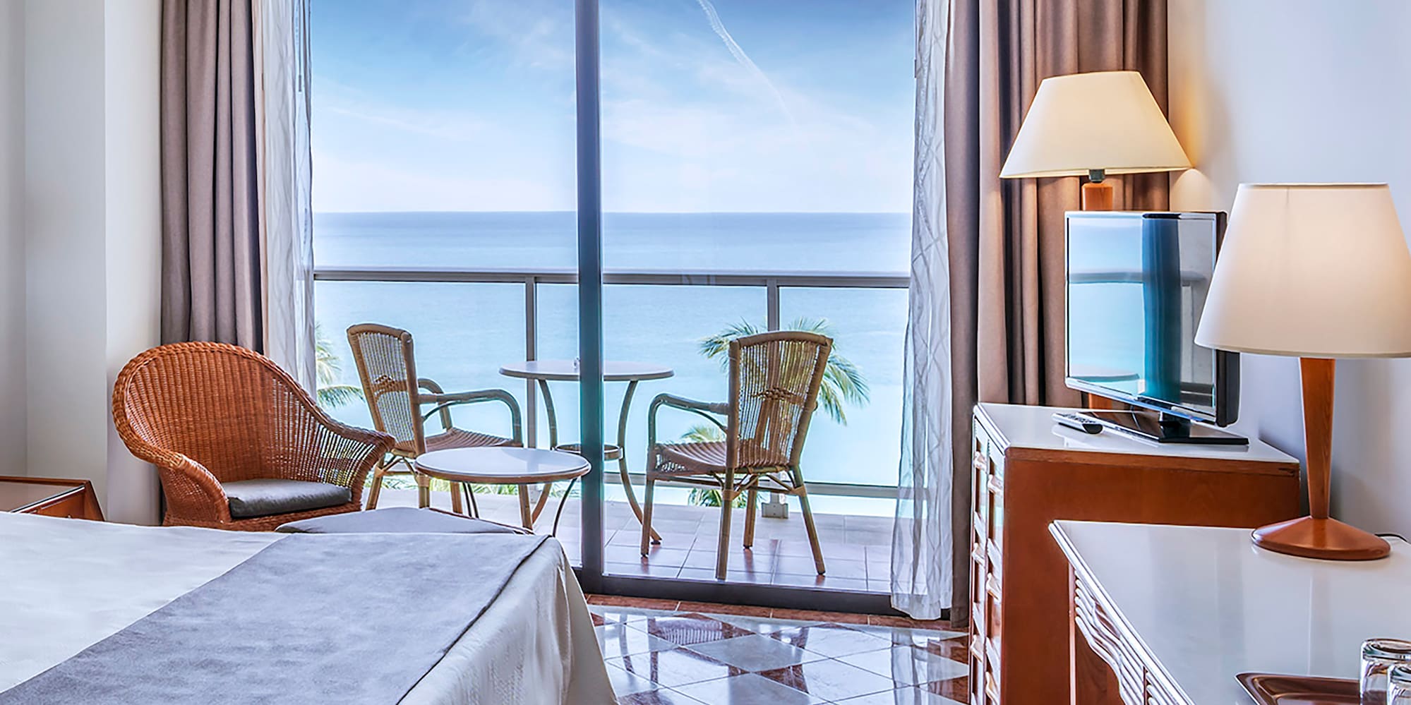 a room with a bed and a table and chairs and a balcony