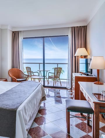 a room with a bed and a table and chairs and a balcony