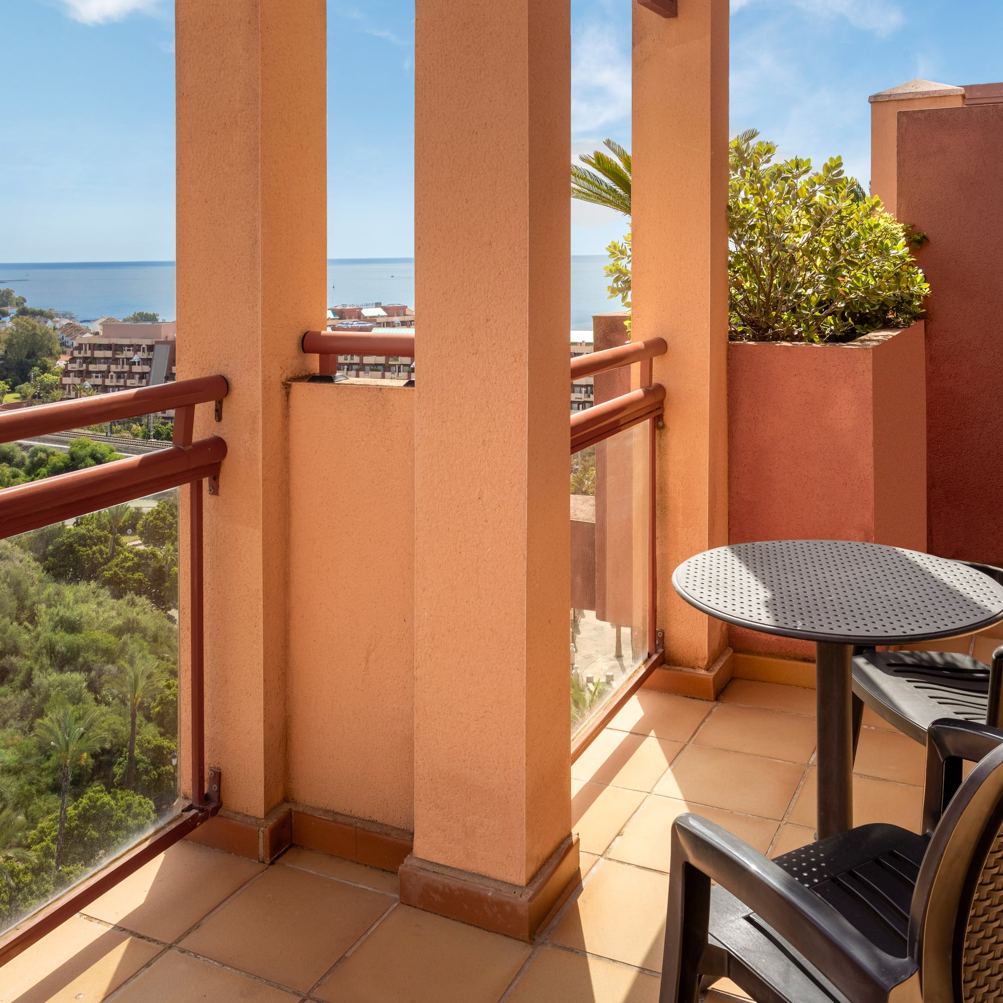 Terracotta balcony with outdoor seating, scenic sea view, and coastal resort.