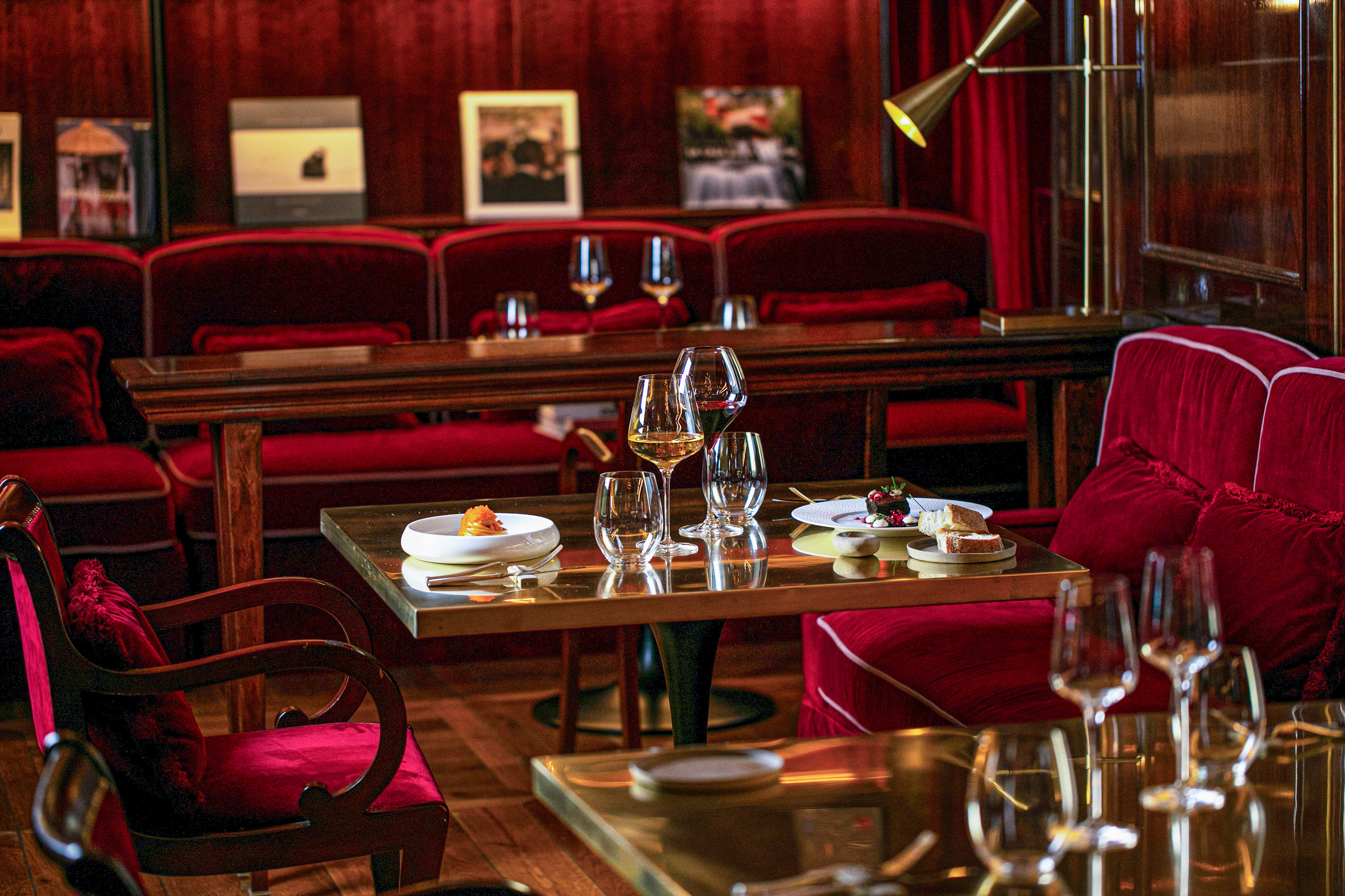 Elegant fine dining room with red velvet seats, wine, and small plates.
