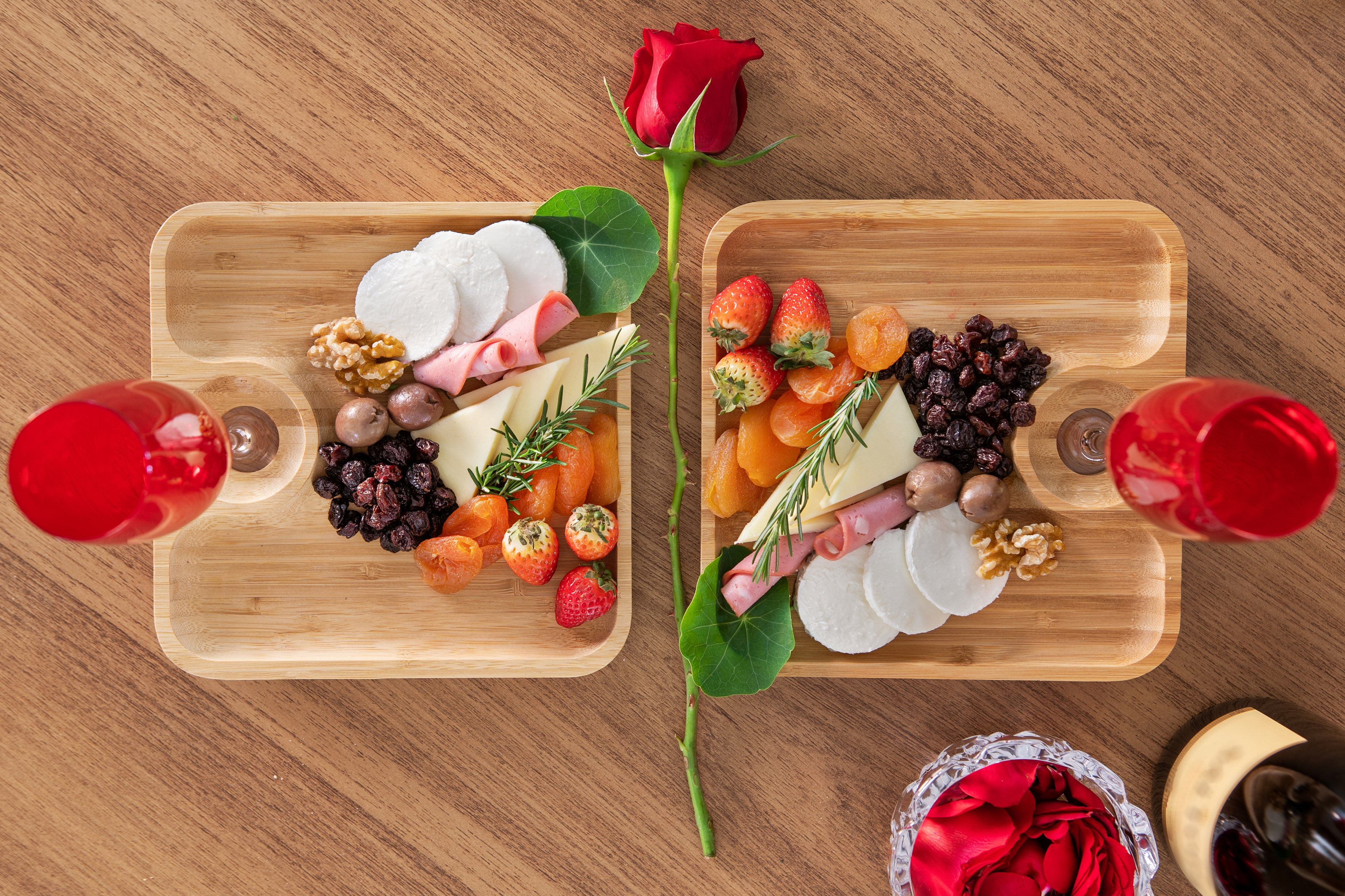 Charcuterie boards with cheese, fruit, nuts, wine, and a red rose.
