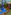 Colorful mini golf clubs in blue stand, yellow ball on artificial putting green.