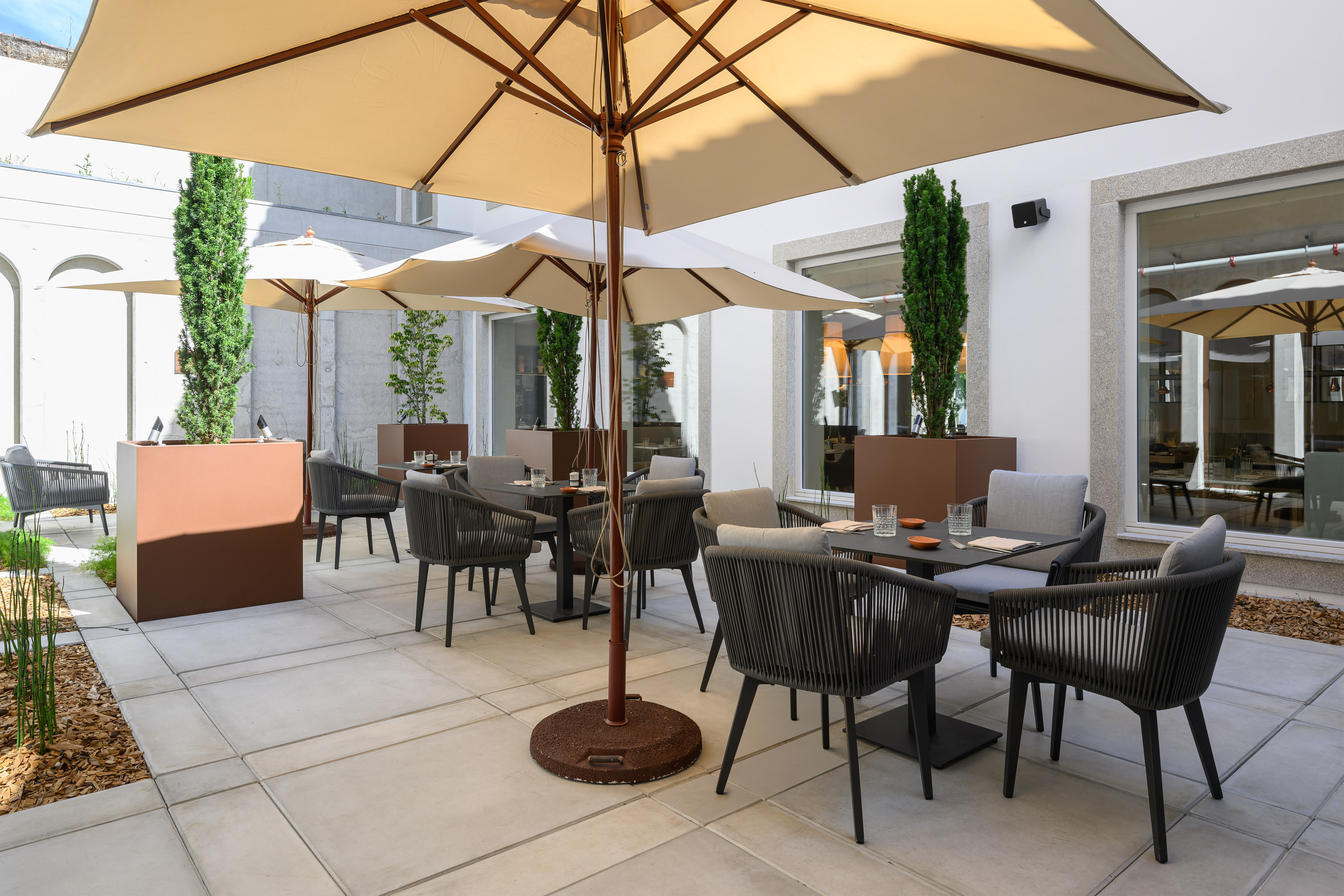 Modern outdoor dining terrace with umbrellas, dark chairs, and potted greenery. - INNSiDE Braga Centro, 브라가
