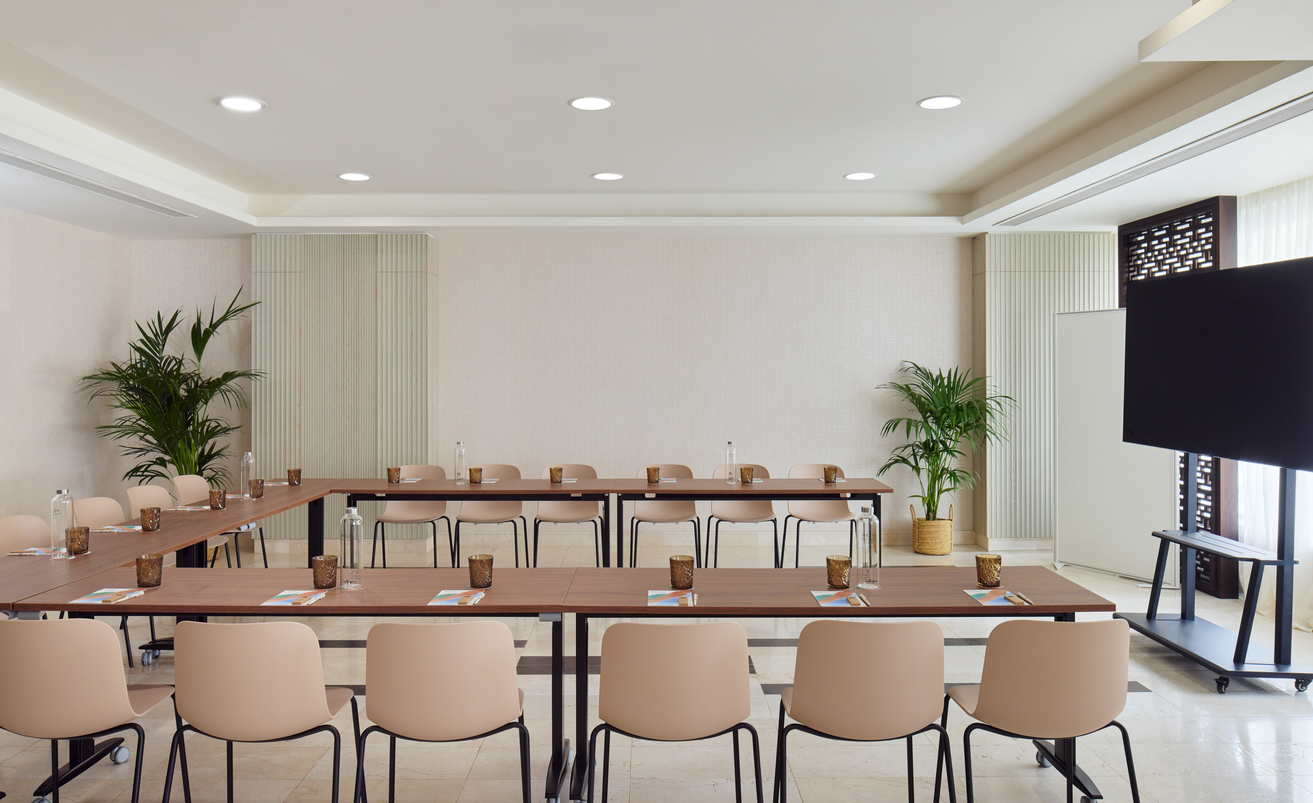 U-shape conference room with modern tables, chairs, and presentation screen.