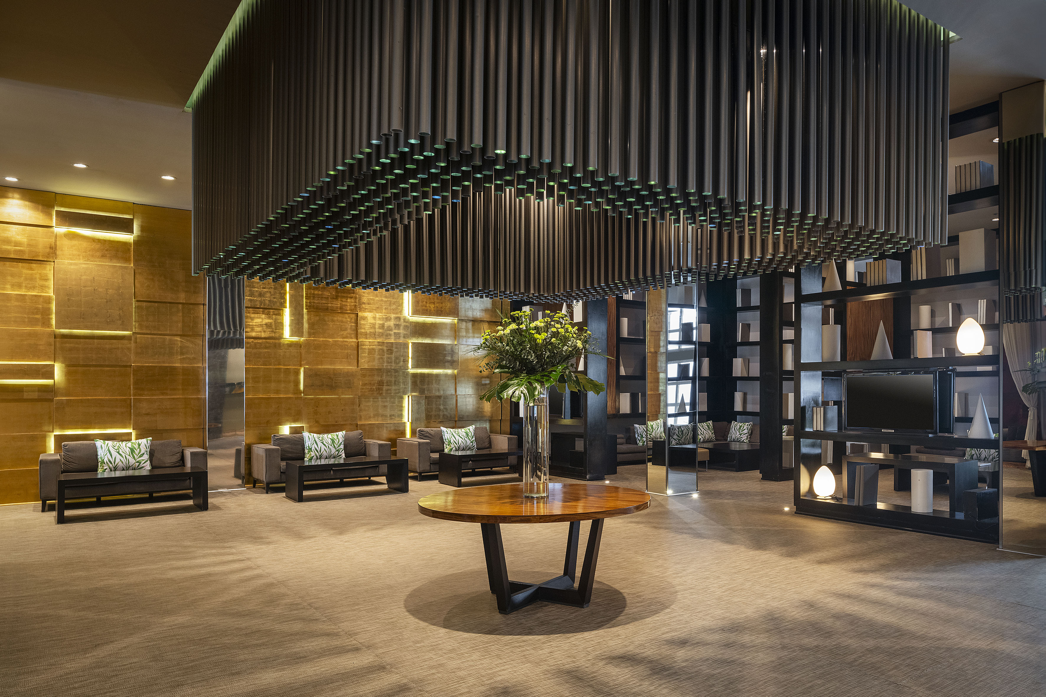 Modern hotel lobby with golden walls, lounge seating, and unique ceiling.